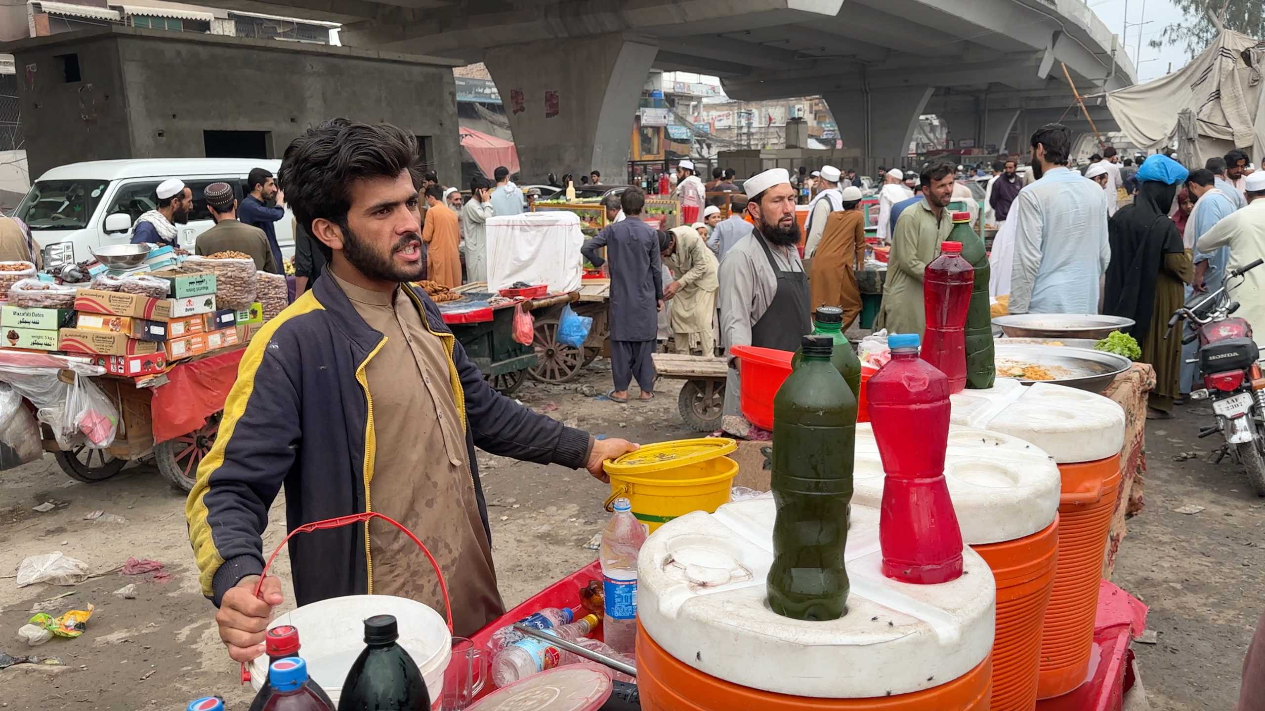 Vendor passionately selling beverages amidst the market's lively atmosphere.