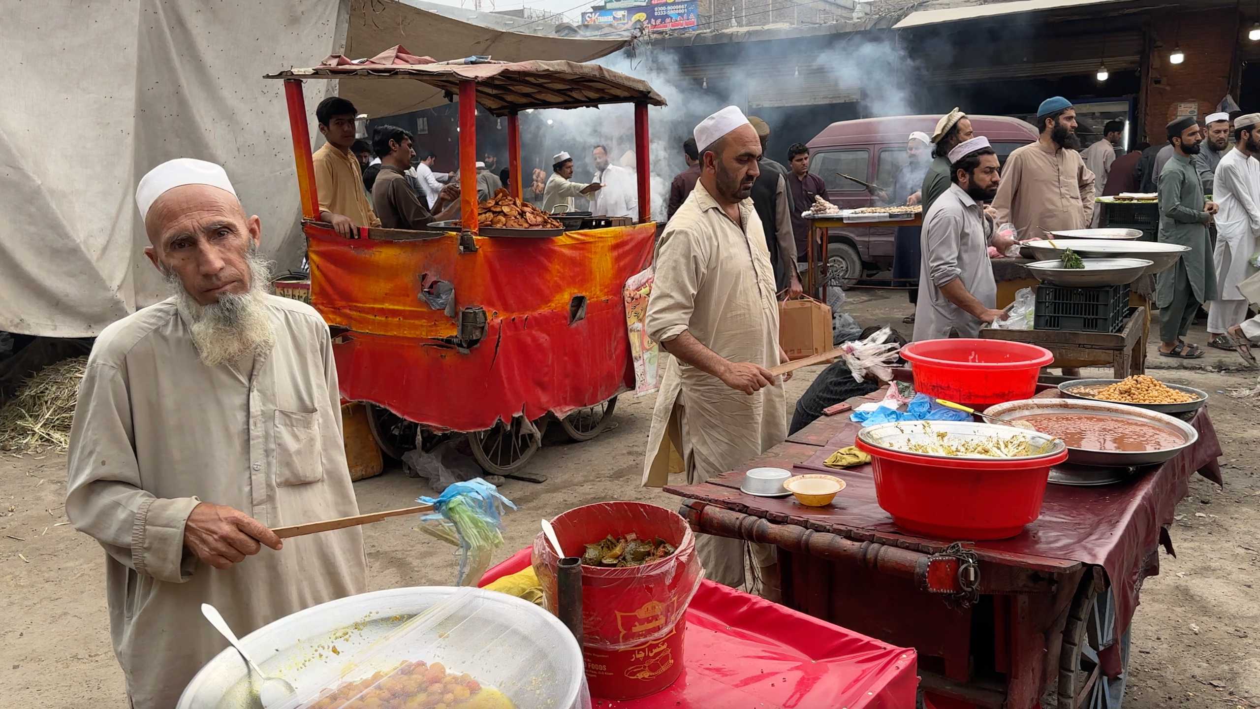 Elderly man and fellow vendors offering a variety of traditional snacks.