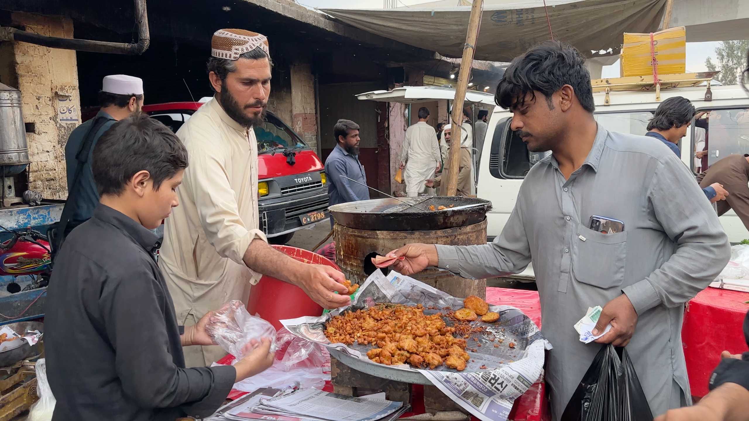 Crispy fried snacks being prepared and sold to eager buyers.