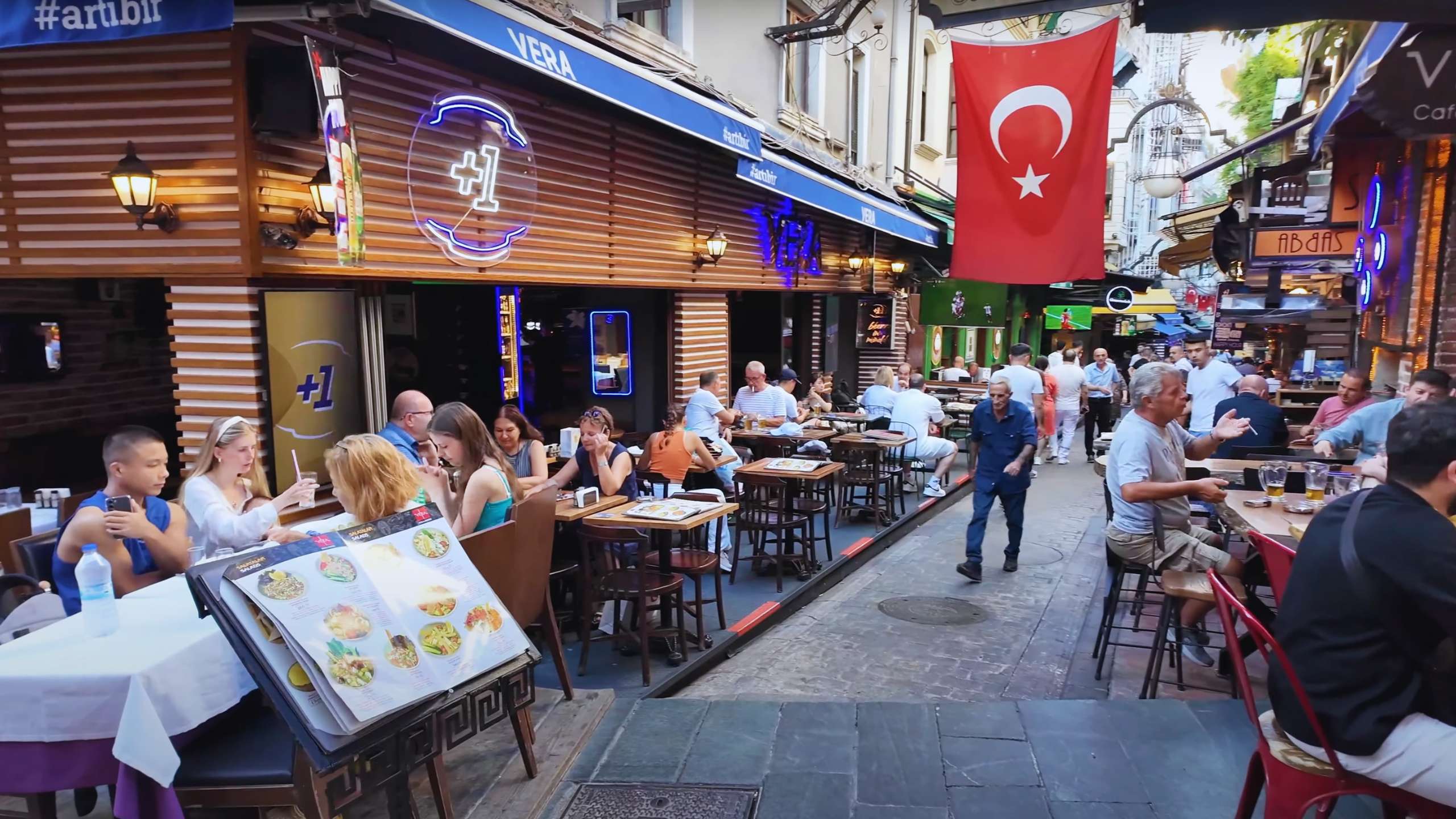 Lively outdoor café setting with patrons dining under the Turkish flag in the heart of Istanbul.