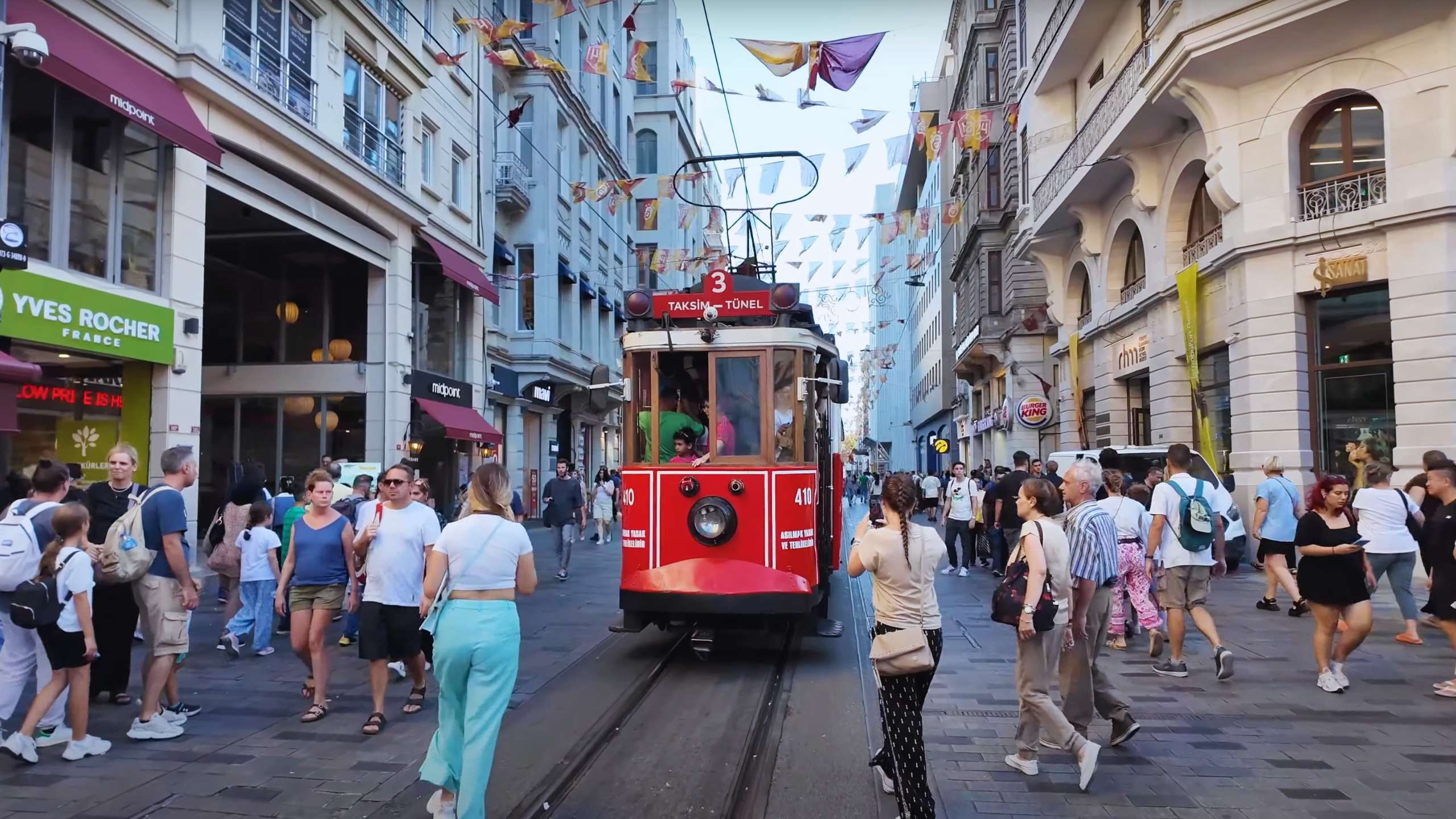 Iconic red tram surrounded by people as it rolls down Istiklal Avenue, a classic Istanbul experience.