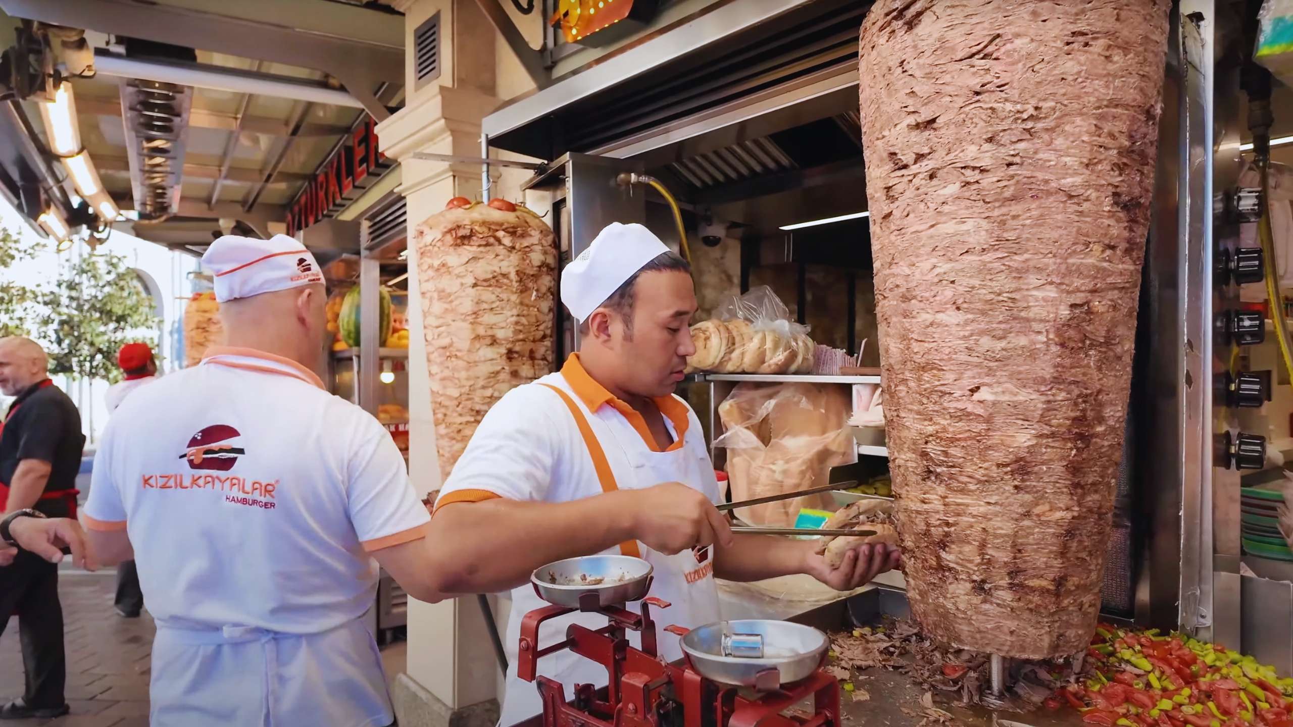 Skilled cooks slicing döner meat from tall, rotating skewers for hungry locals.