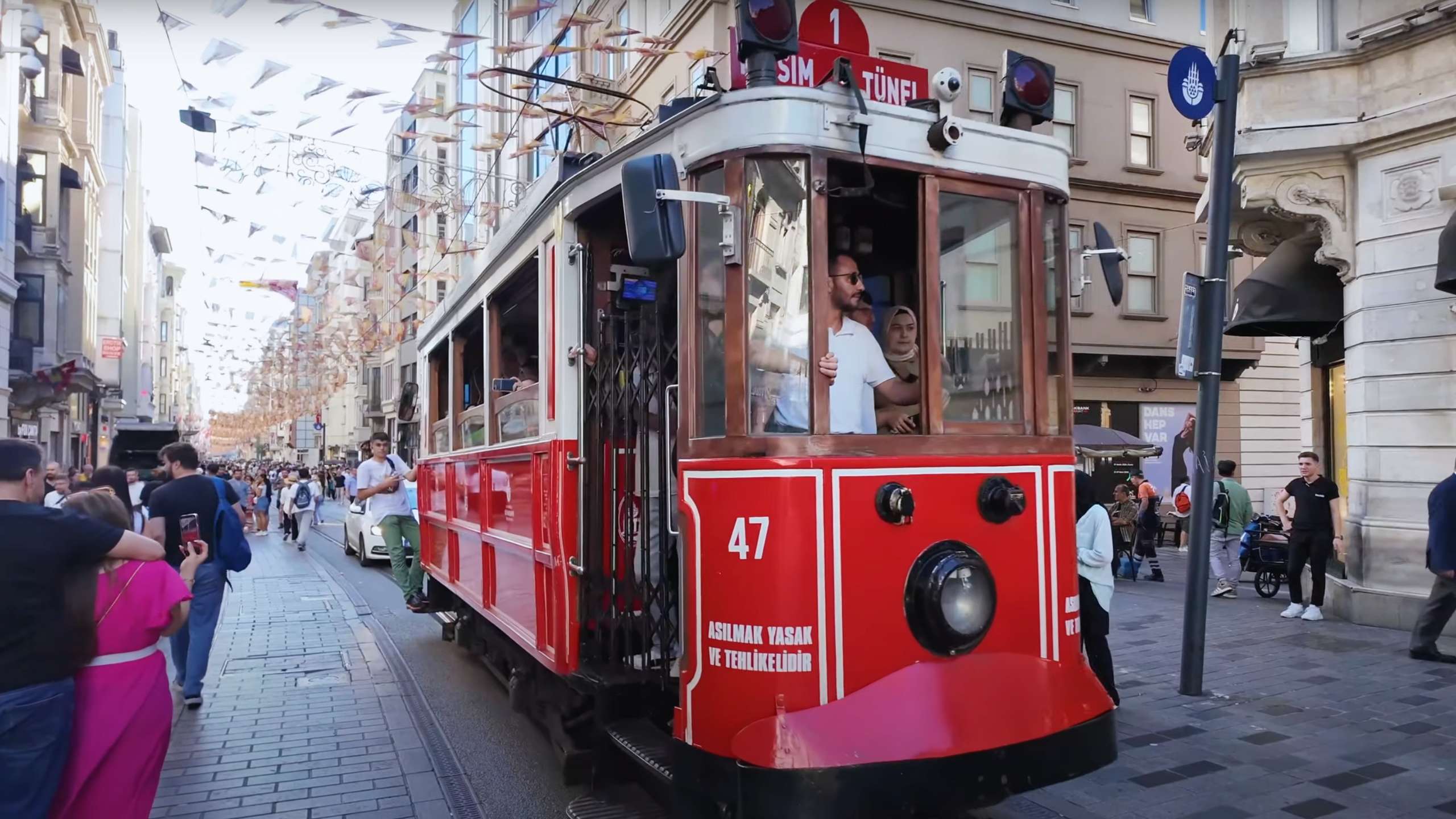 Historic red tram making its way down Istiklal Avenue, carrying cheerful passengers.