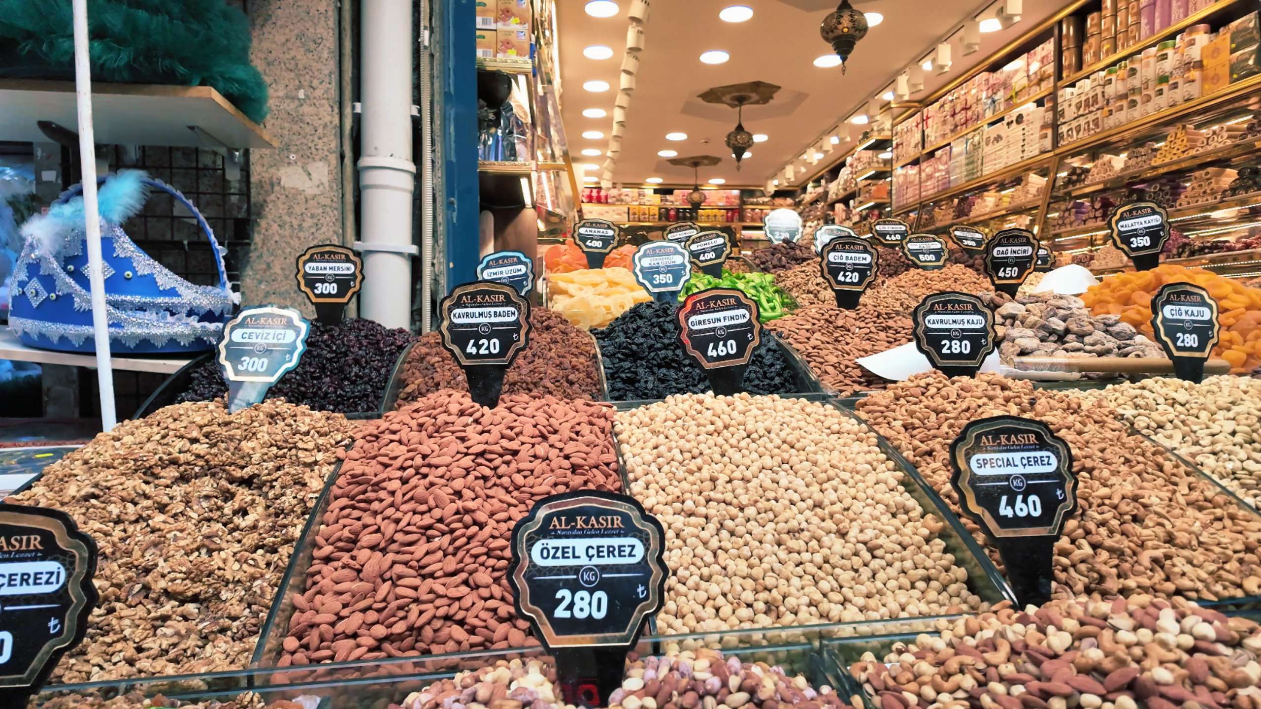 A variety of nuts and dried fruits displayed with price labels in a shop.