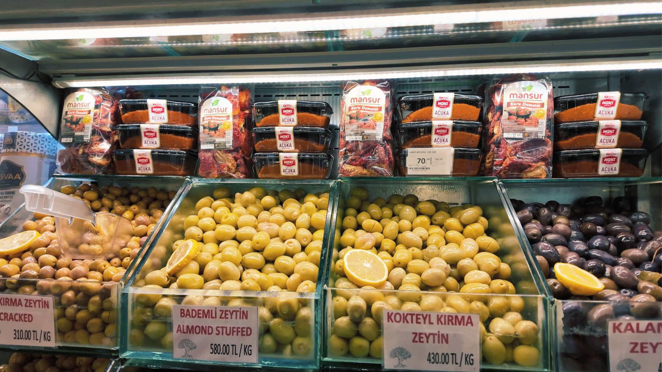 An assortment of green, black, and stuffed olives neatly organized for sale.