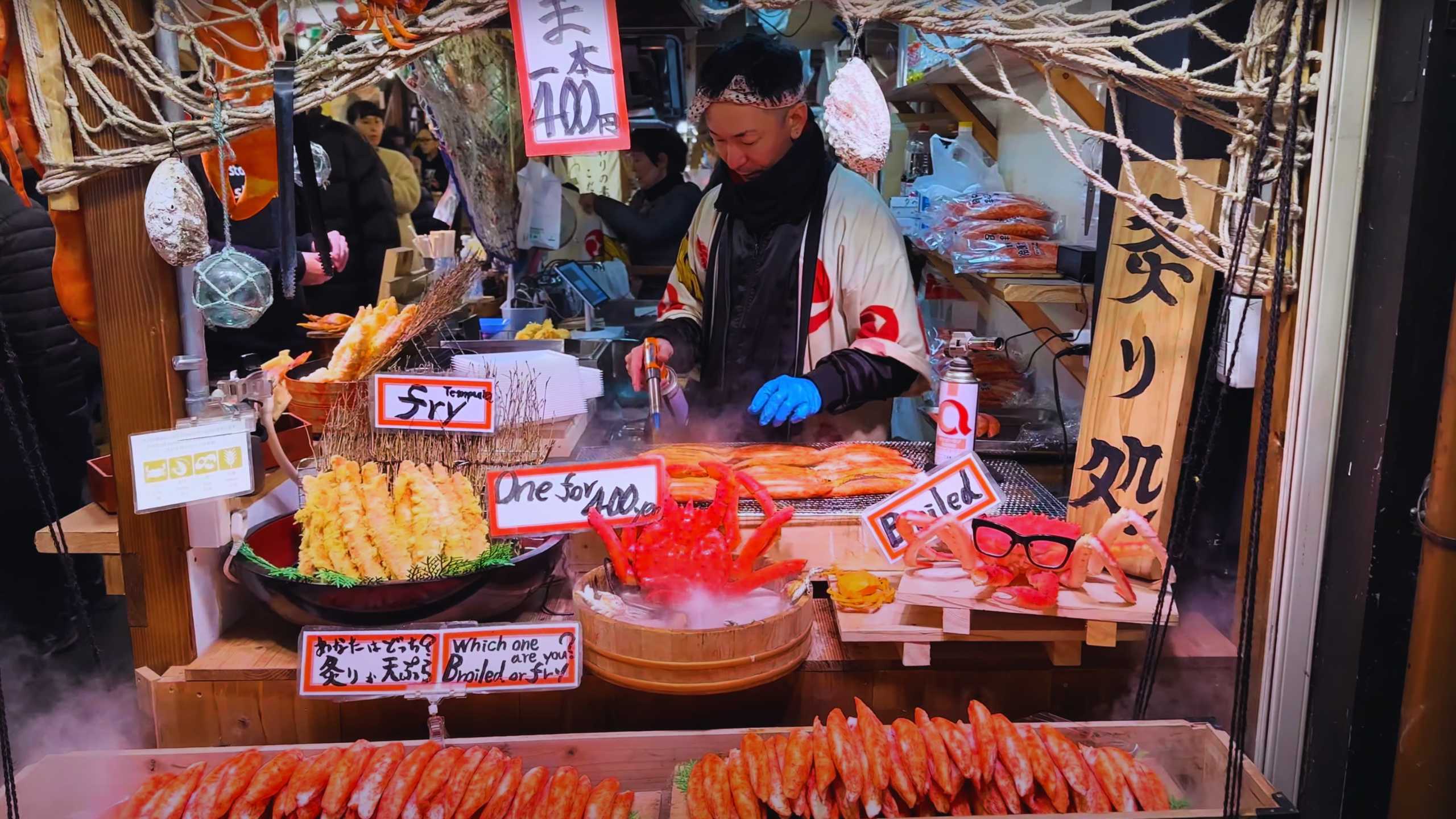 Seller grilling seafood and selling tempura and crab legs.