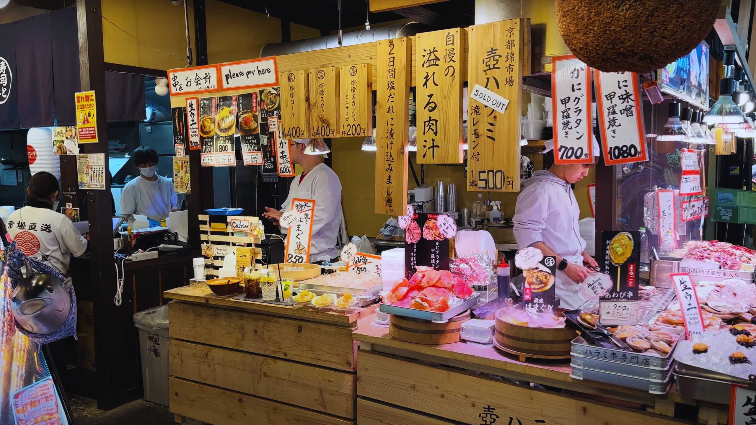 Seafood stall offering crab, sushi, and sashimi with vibrant signage.