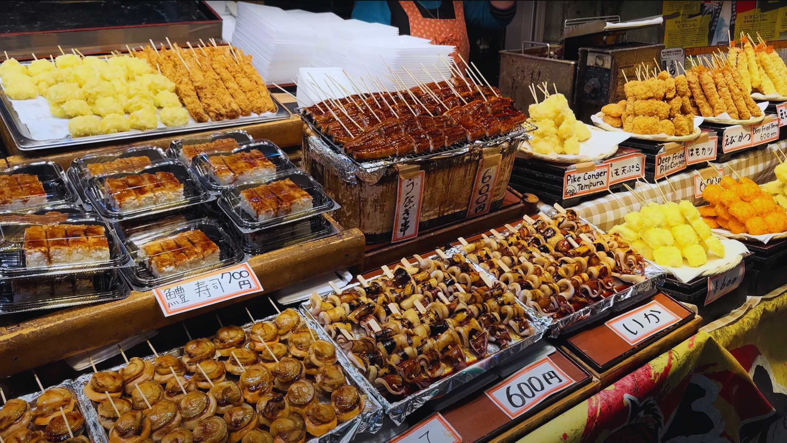 Assorted grilled and fried seafood skewers and sushi on display.