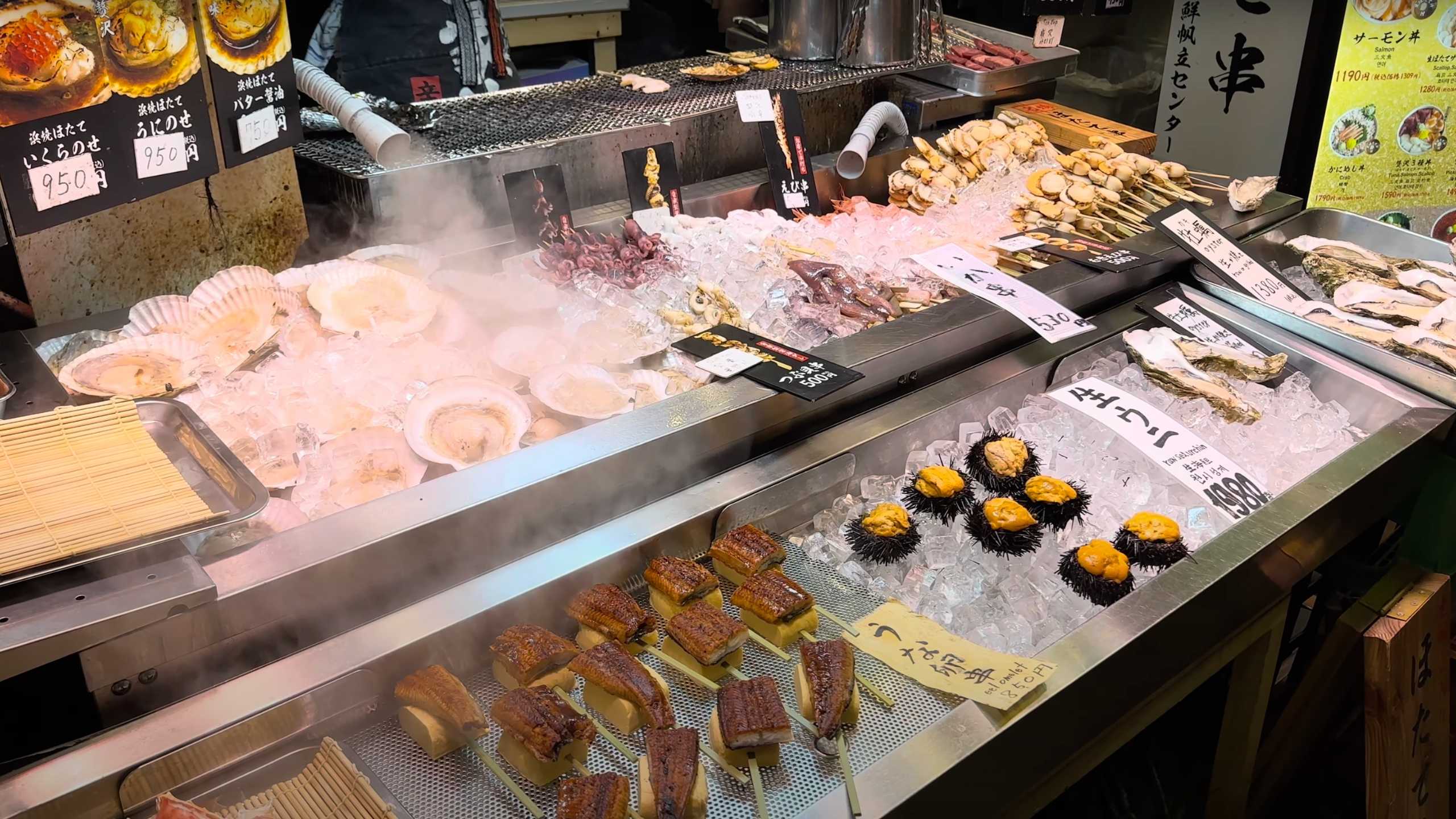 Iced seafood display featuring scallops, squid skewers, and sea urchins.