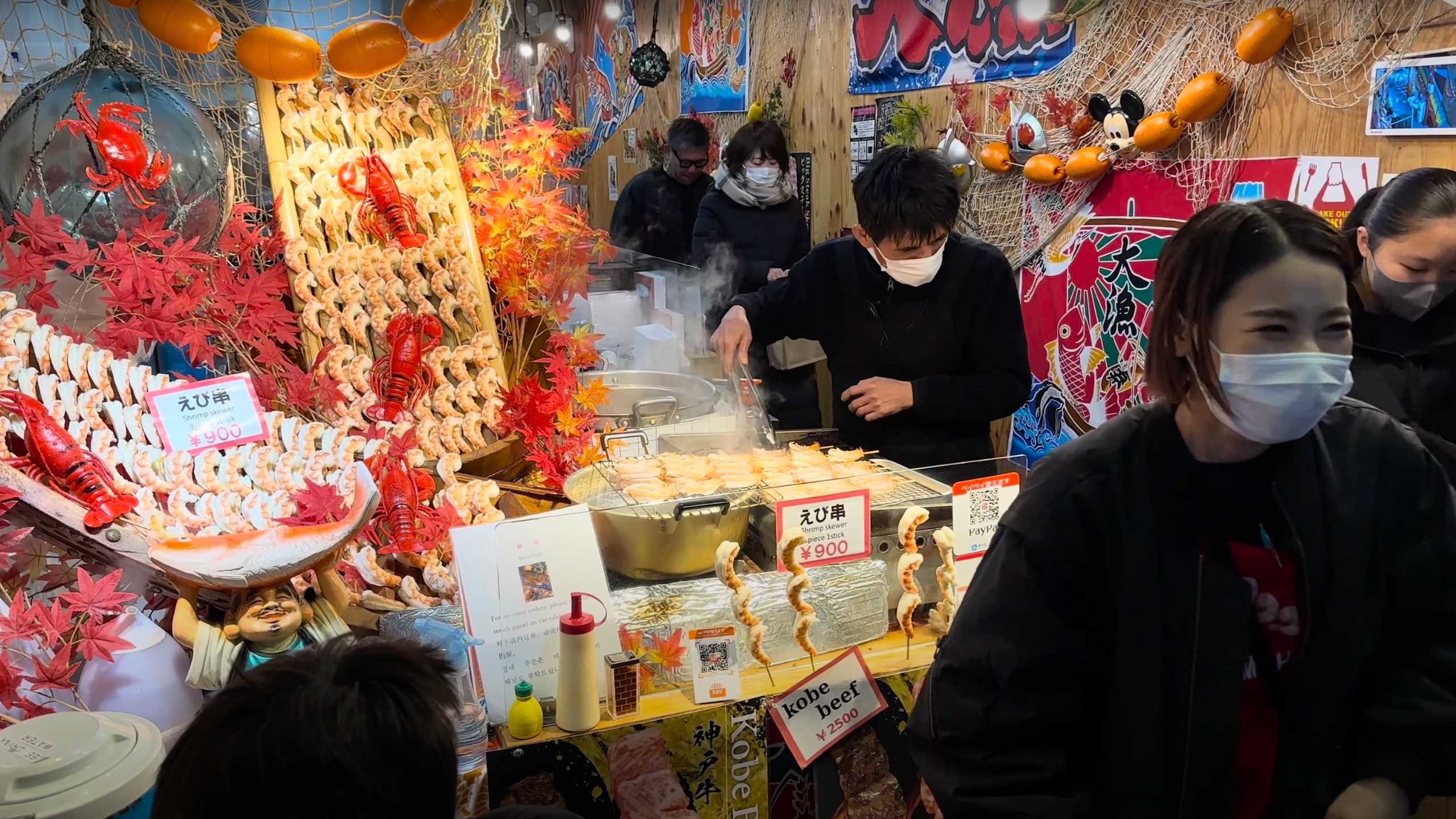 Shoppers enjoy grilled shrimp skewers at a colorful seafood stall.