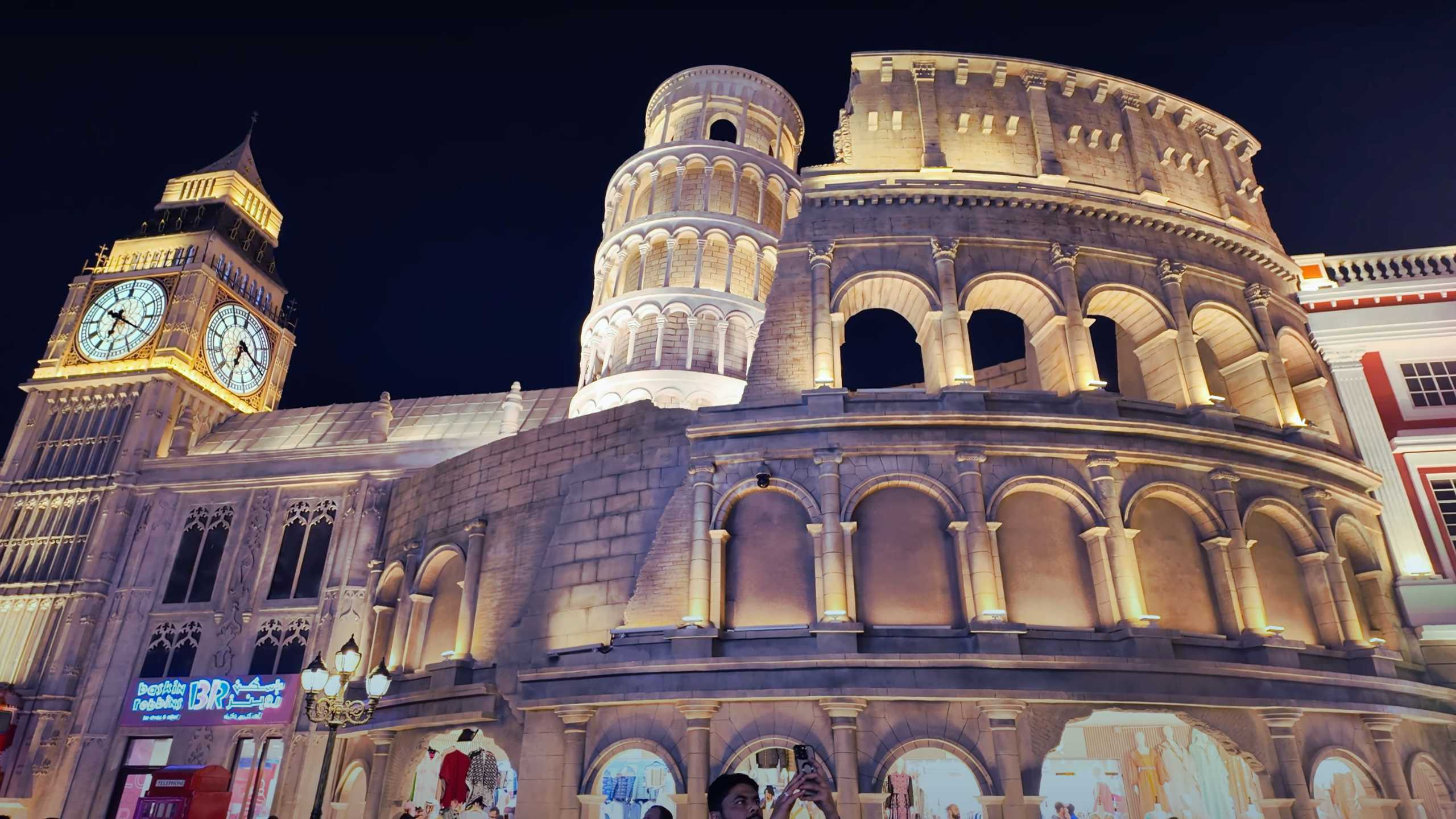 Iconic replicas of European landmarks, glowing under the night sky.