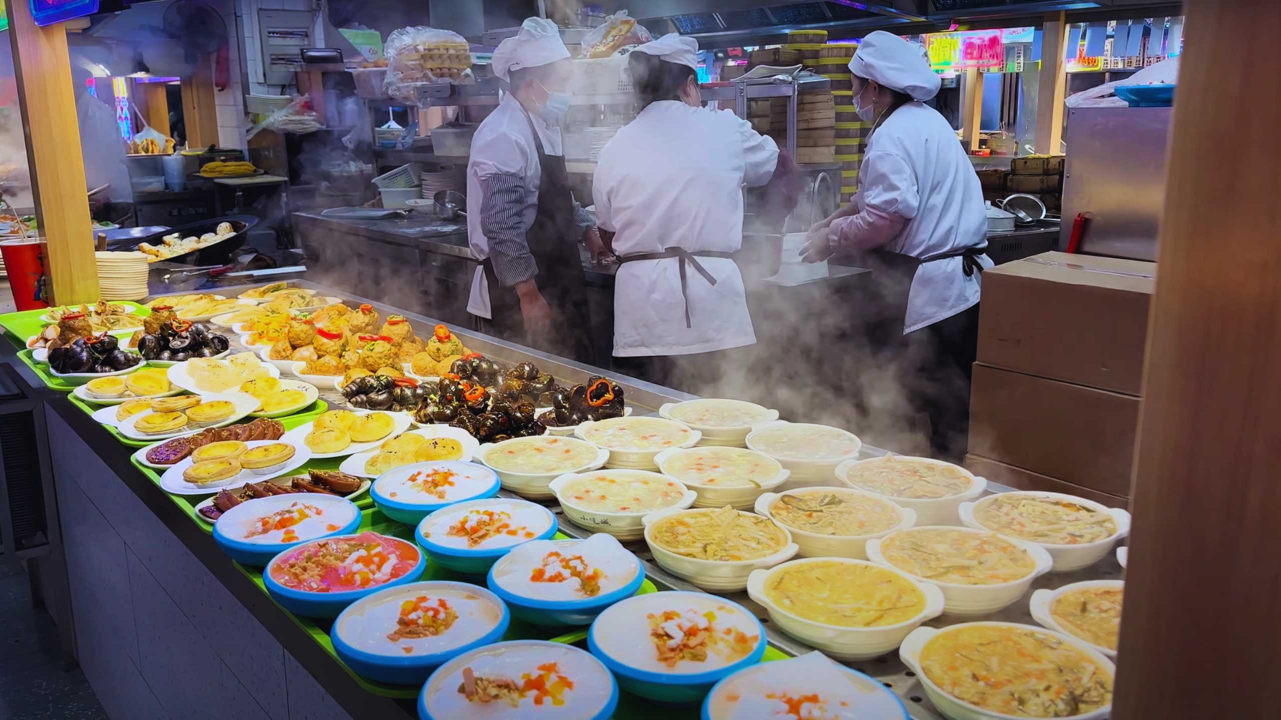 YAn enticing display of steaming hot dishes and traditional snacks at a bustling market stall.