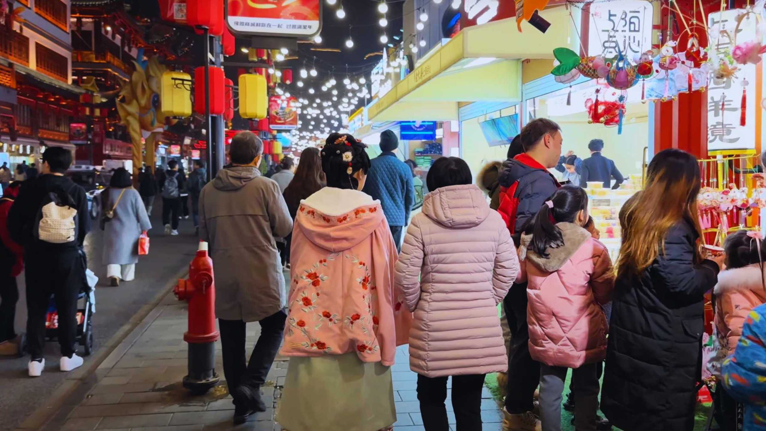 Visitors stroll through the illuminated streets of Yuyuan Bazaar, soaking in the festive atmosphere.