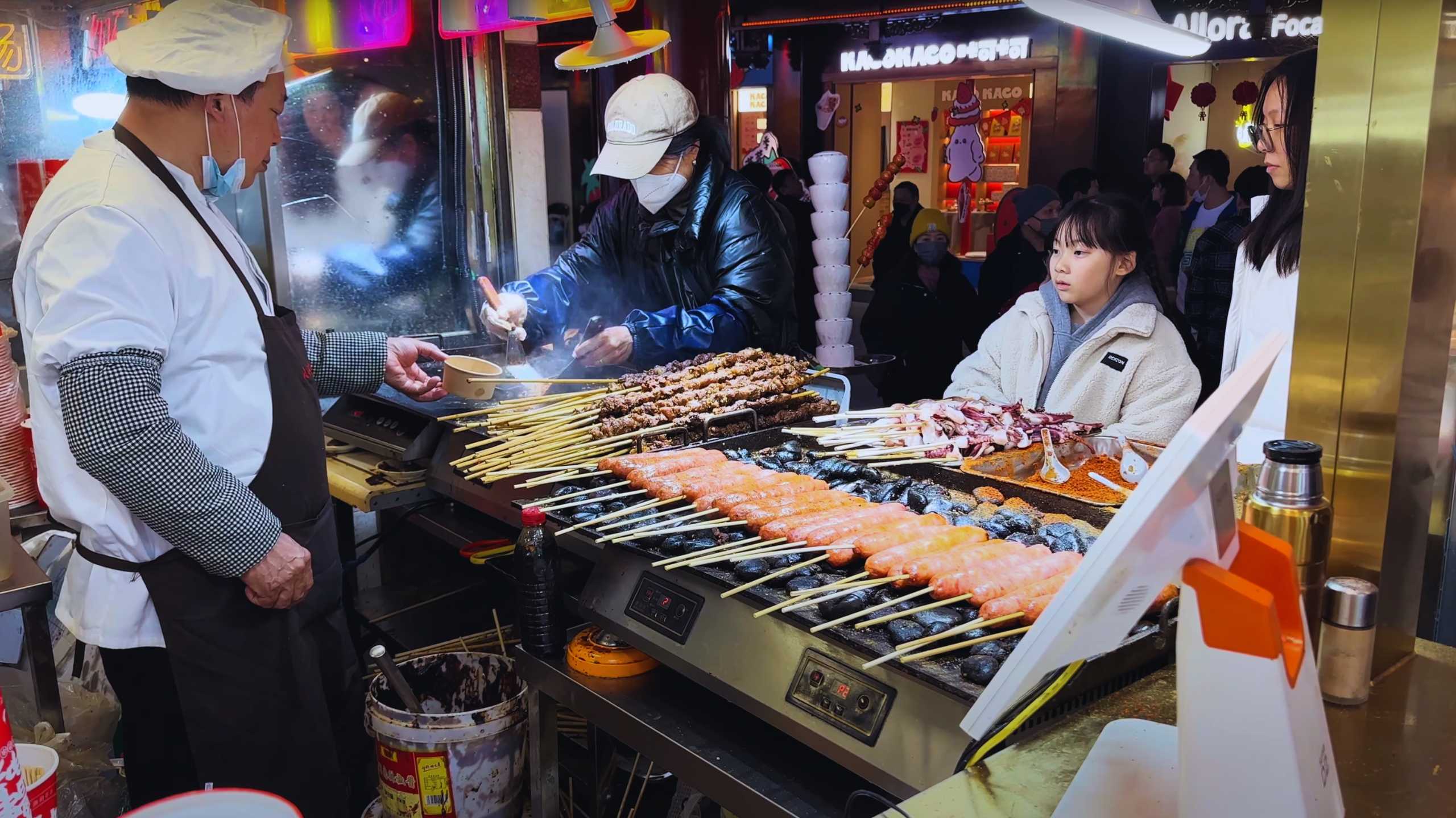 Skewers of delicious grilled meat and seafood sizzling at a bustling street food stall.