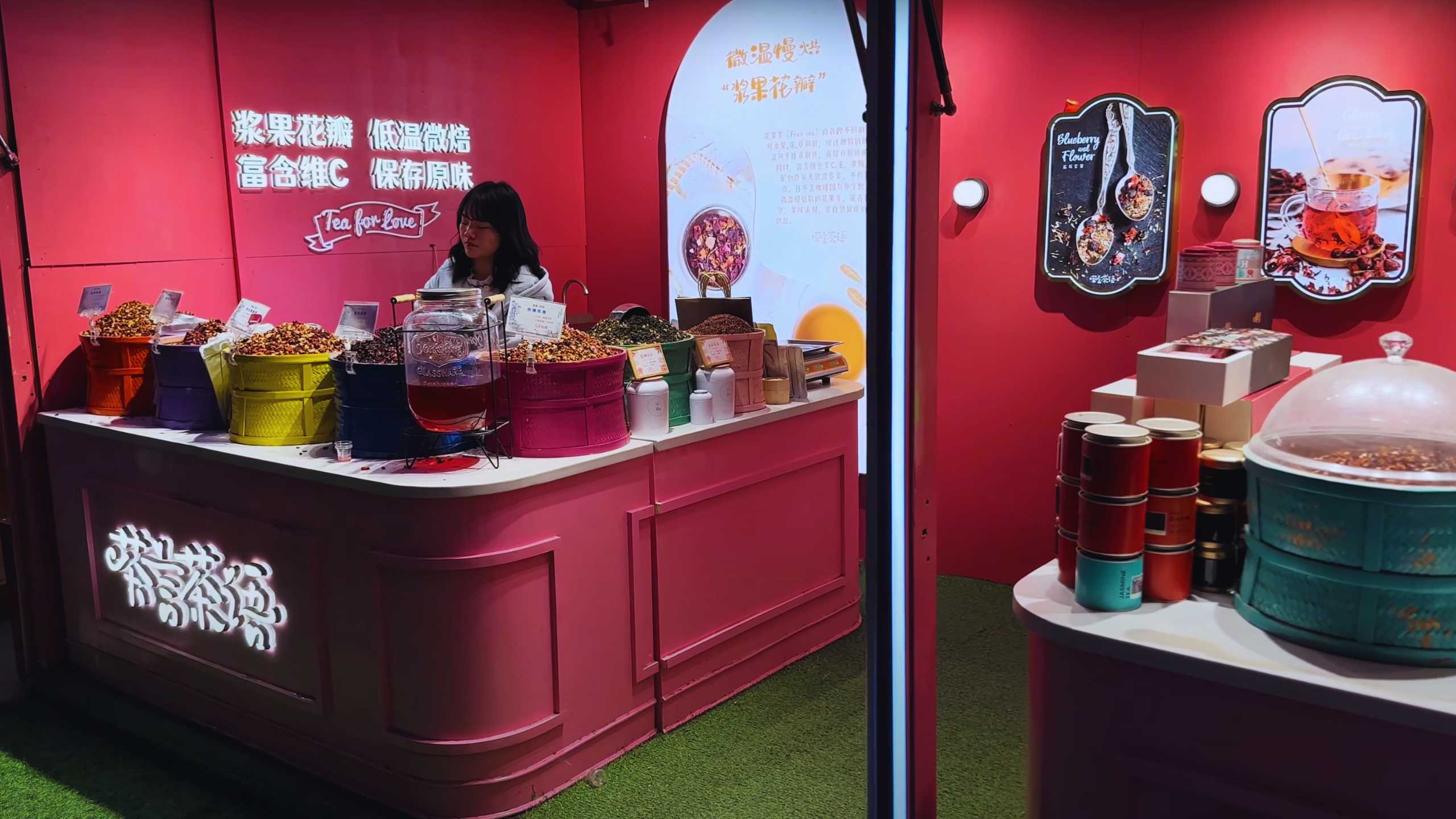 A vendor in a vibrant tea shop, offering a variety of teas and dried goods.