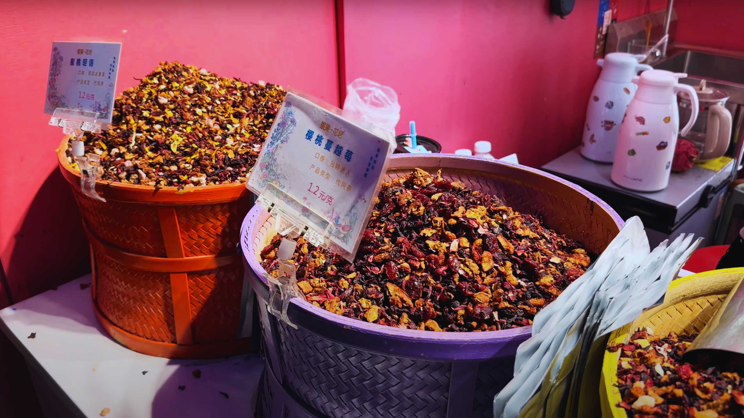 Large containers filled with colorful dried fruits and tea blends at Yuyuan Bazaar.