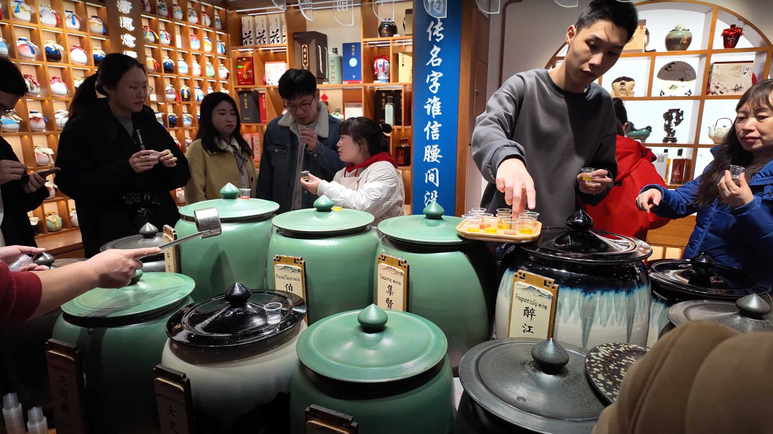 Visitors sampling various traditional Chinese wines in a lively market.