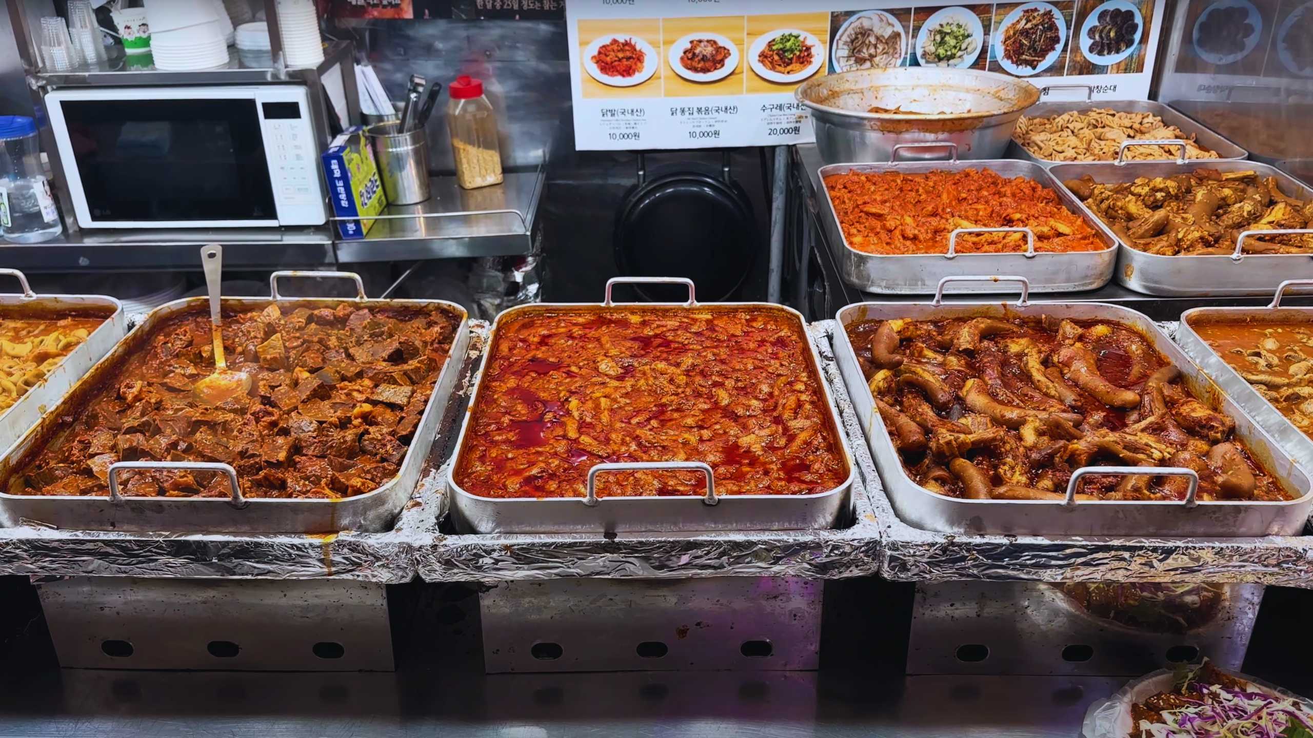 A vibrant display of steaming hot dishes, featuring spicy stews and savory meats, ready to be served.