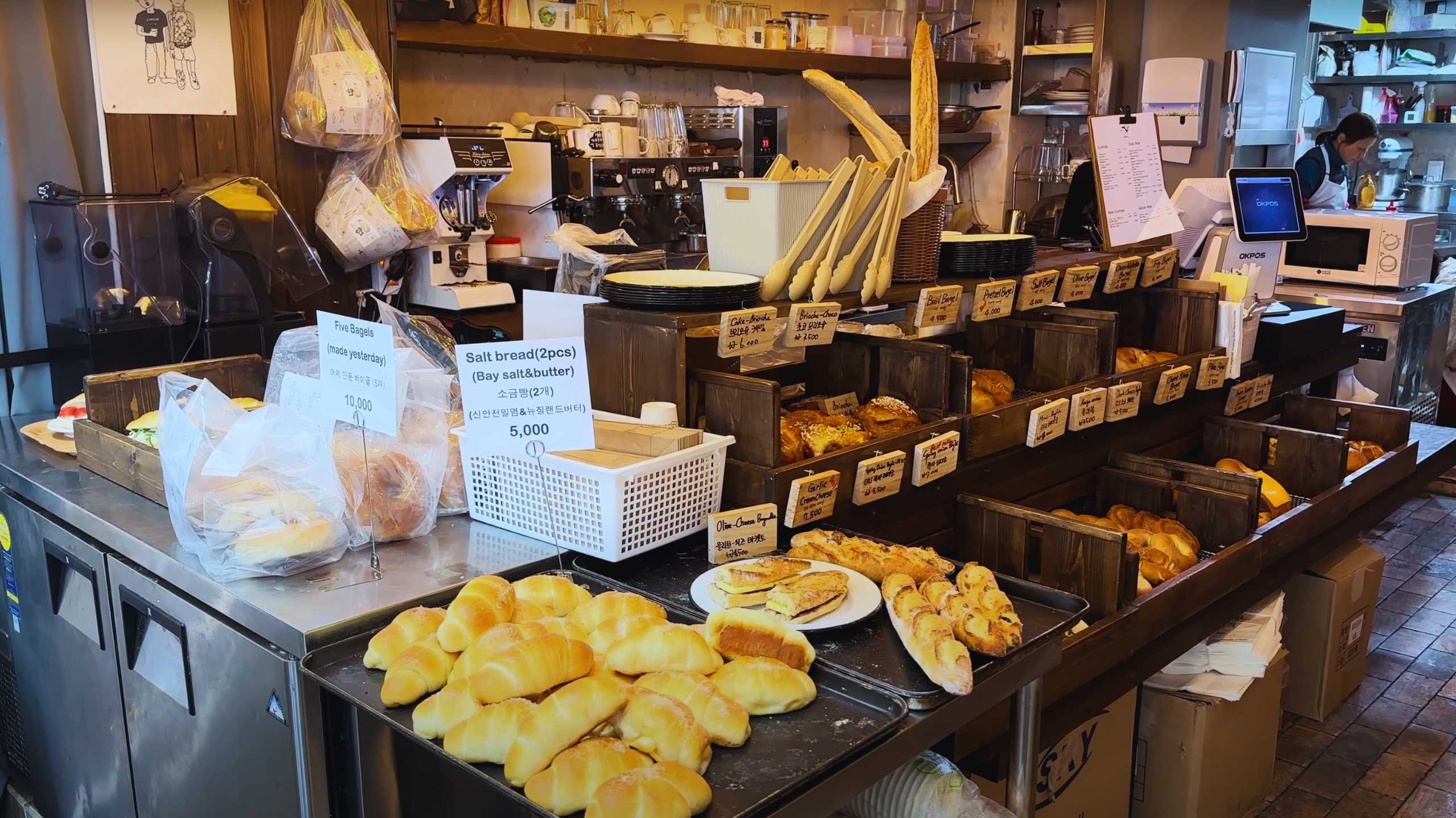 A cozy bakery with a selection of fresh bread and pastries, neatly arranged on wooden shelves.