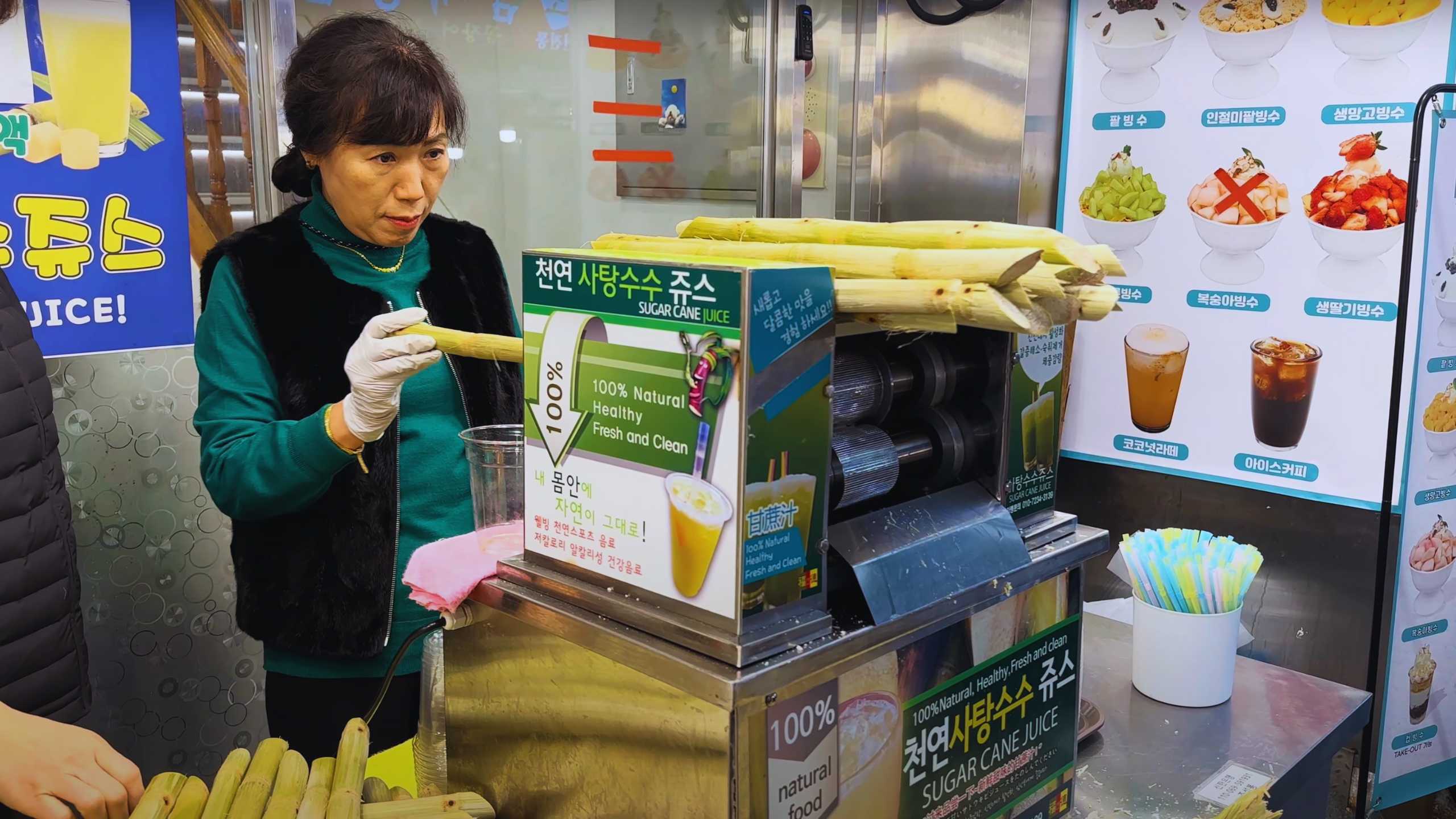 A vendor preparing fresh sugar cane juice, carefully measuring a stalk before pressing.