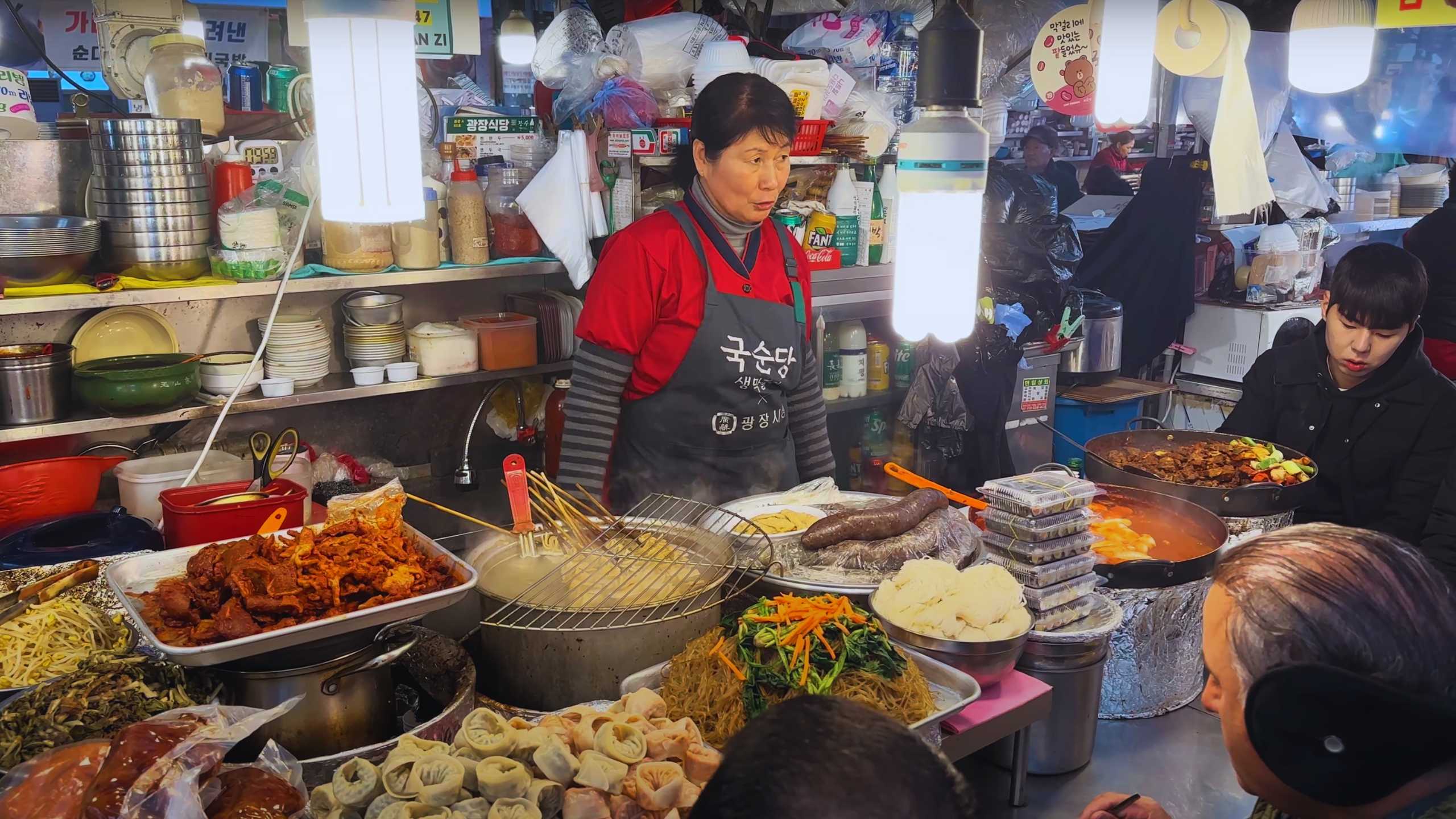 A focused vendor amidst a plethora of prepared dishes, from dumplings to stir-fried vegetables.