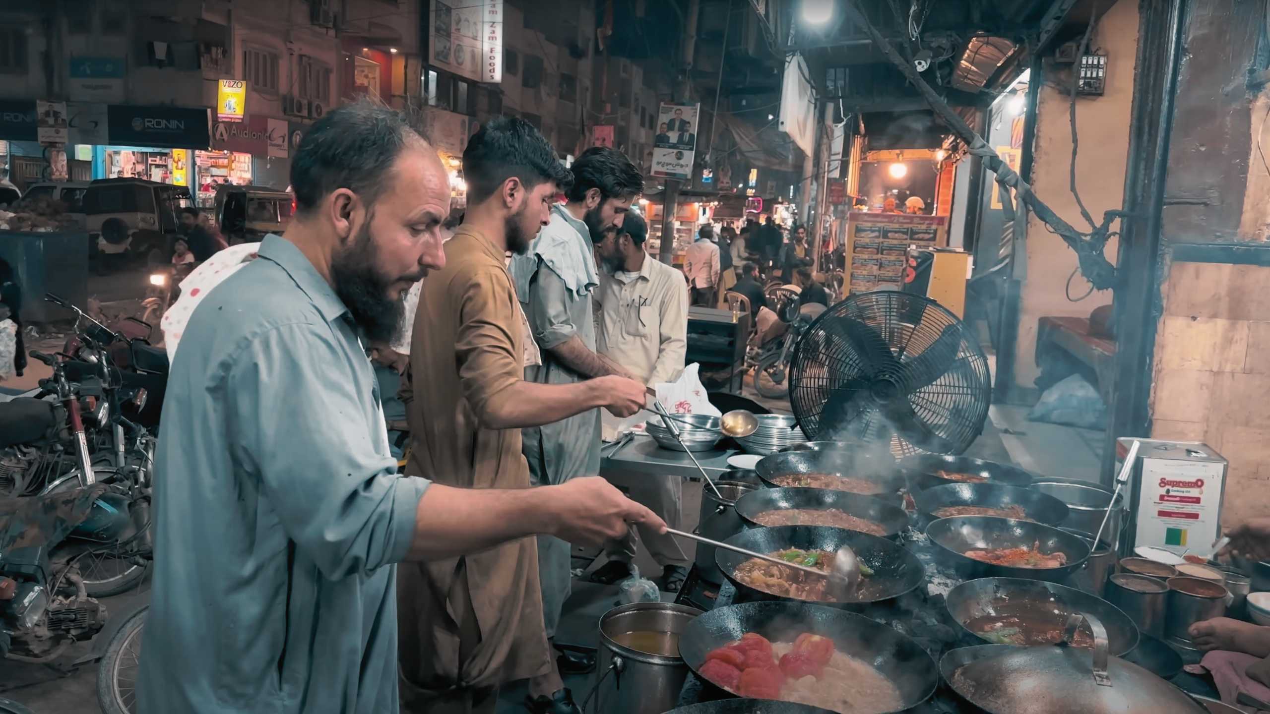 Chefs stirring large woks filled with aromatic curries, their focus unwavering.