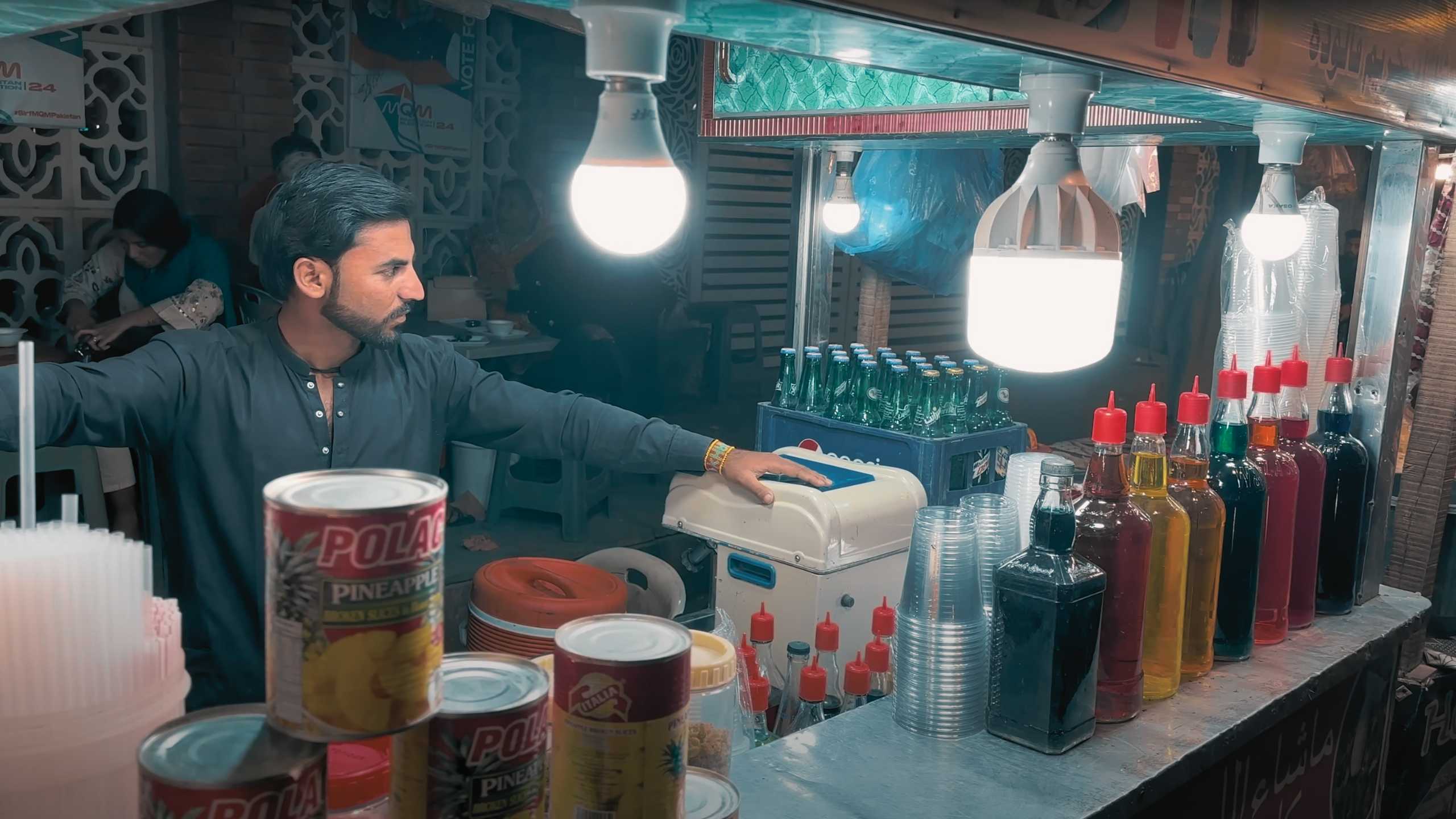 A vendor organizing colorful syrups and beverages, ready to serve refreshing drinks.