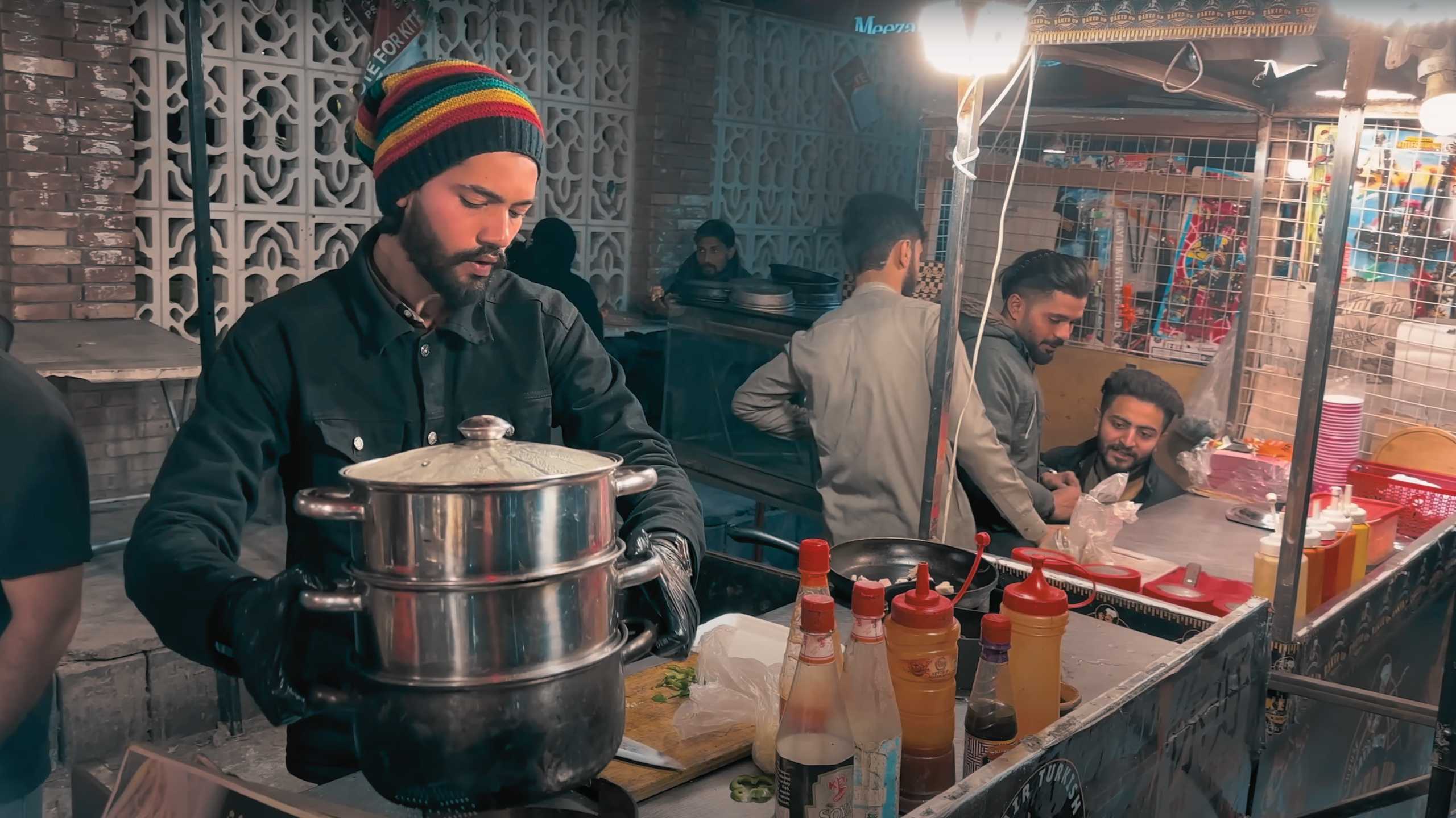 A street chef carefully preparing steaming hot food with a focused expression.