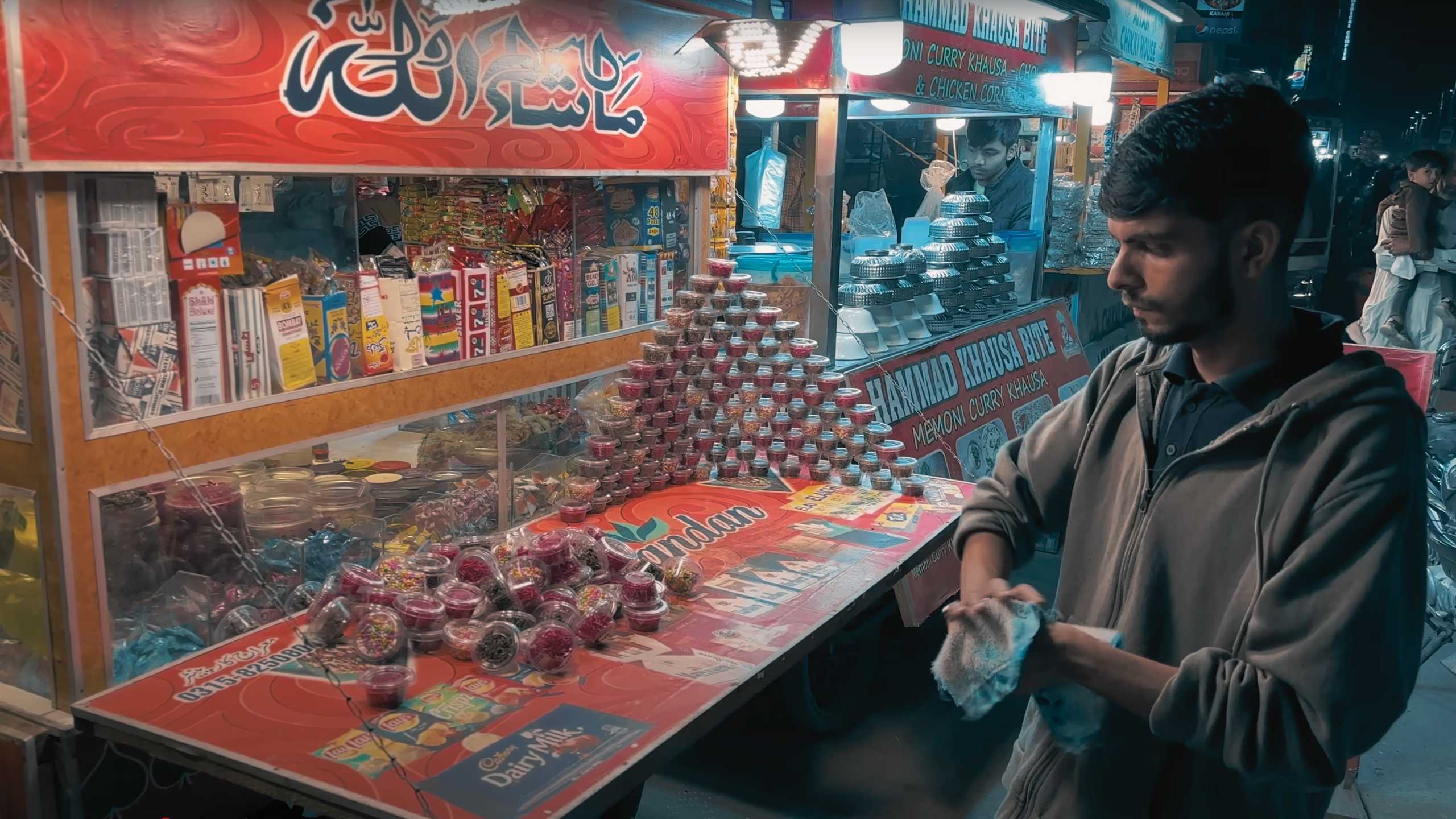 A vendor meticulously organizing sweets and snacks at his stall.