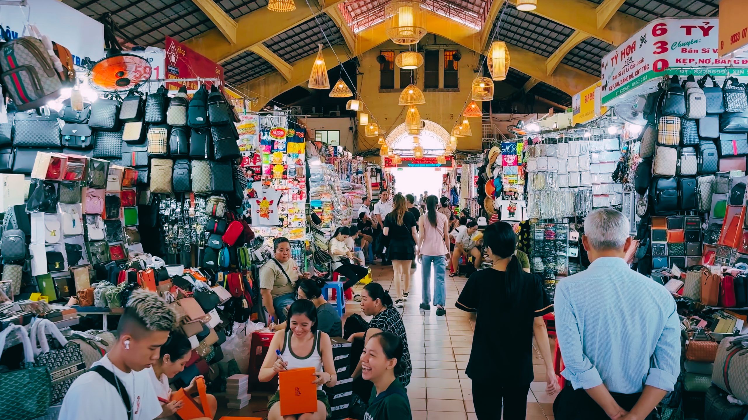 A lively shopping aisle full of backpacks, fashion and happy market-goers.