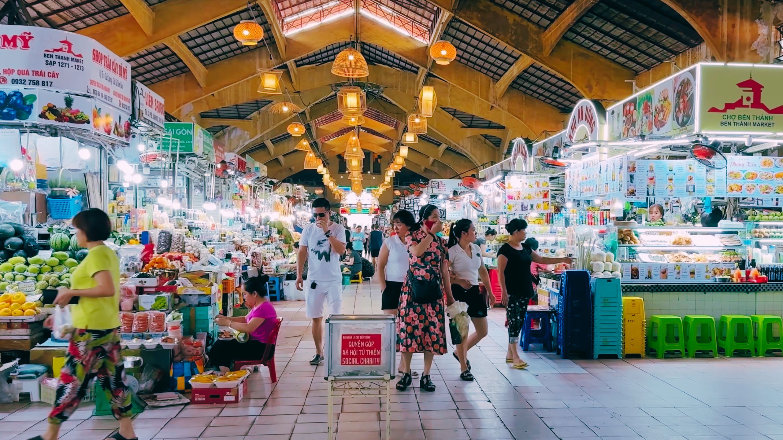 Colorful indoor stalls selling fruits, snacks and souvenirs line the busy central aisle.