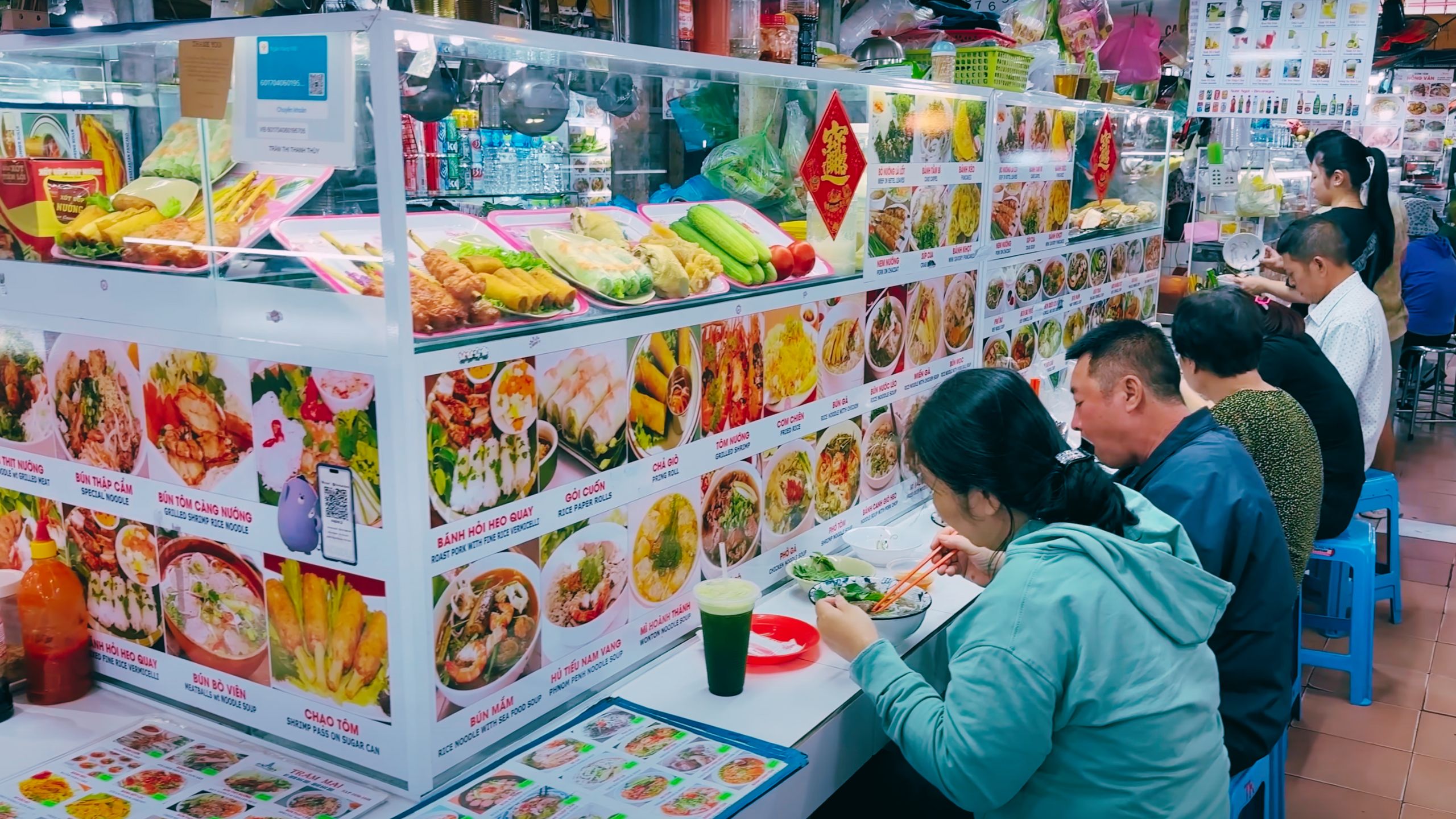 Locals enjoy pho and rice dishes at a busy street food stall in the market.