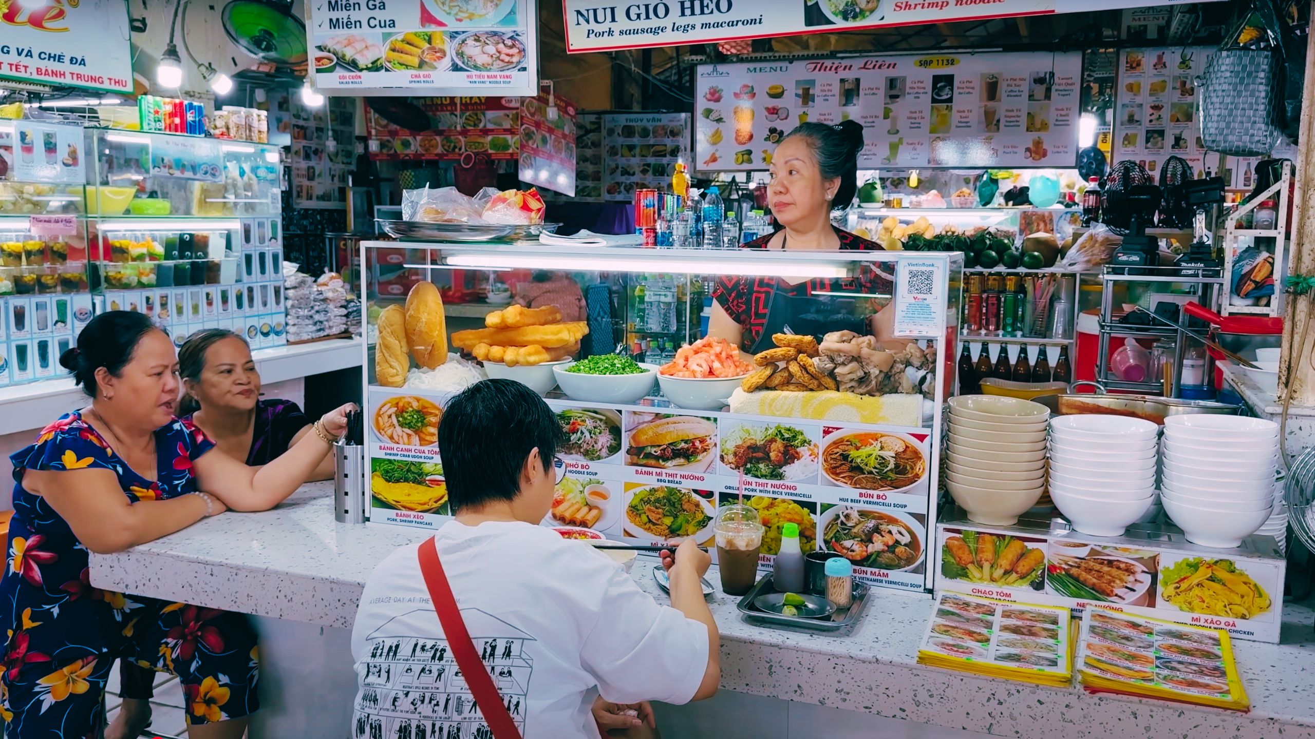 Diners enjoy hot noodle soups and grilled pork at a welcoming food counter.