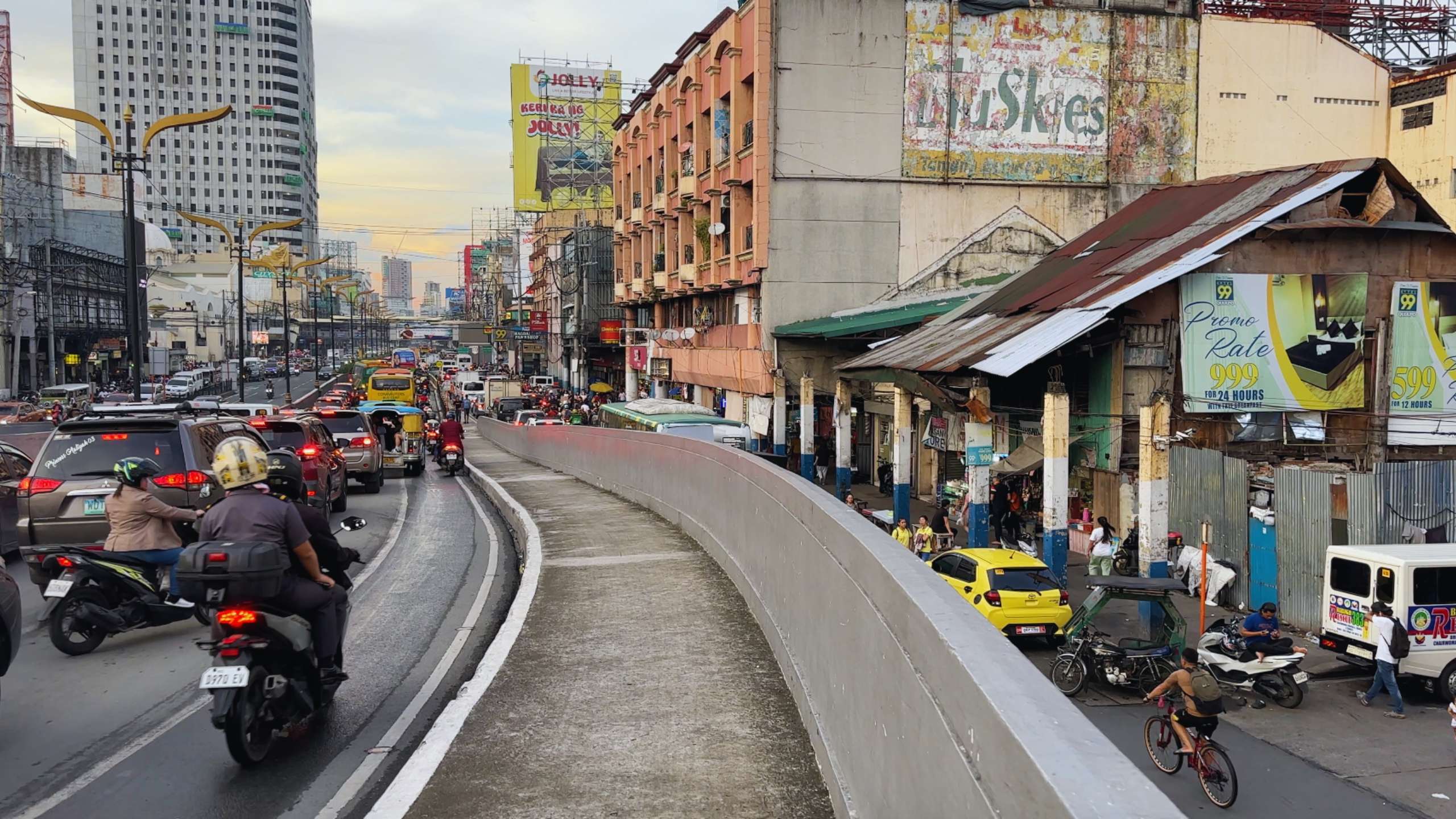 Heavy traffic flows along a crowded Manila street lined with shops and billboards.