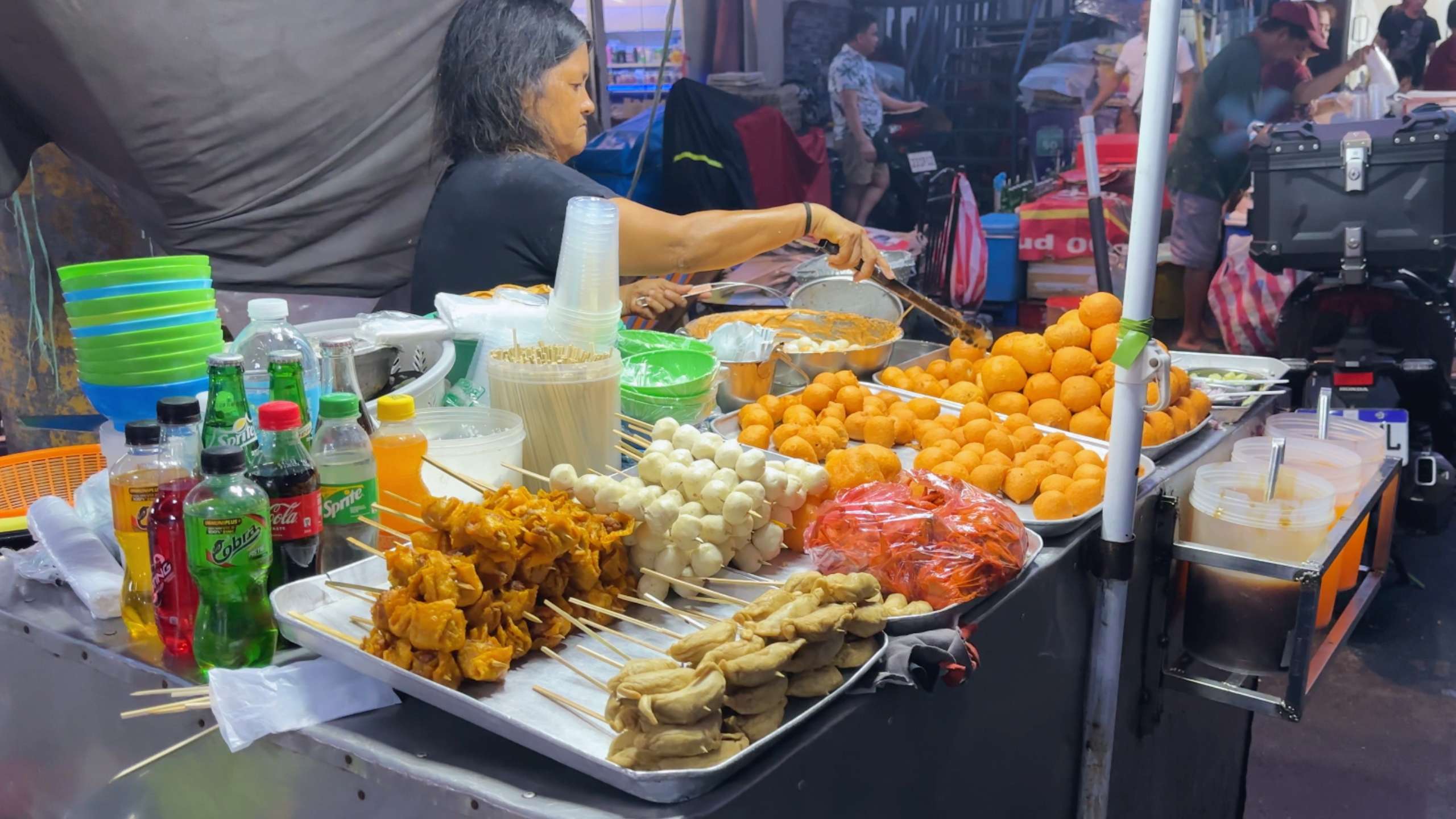 A street food stall offering skewered snacks and refreshing drinks in vibrant colors.