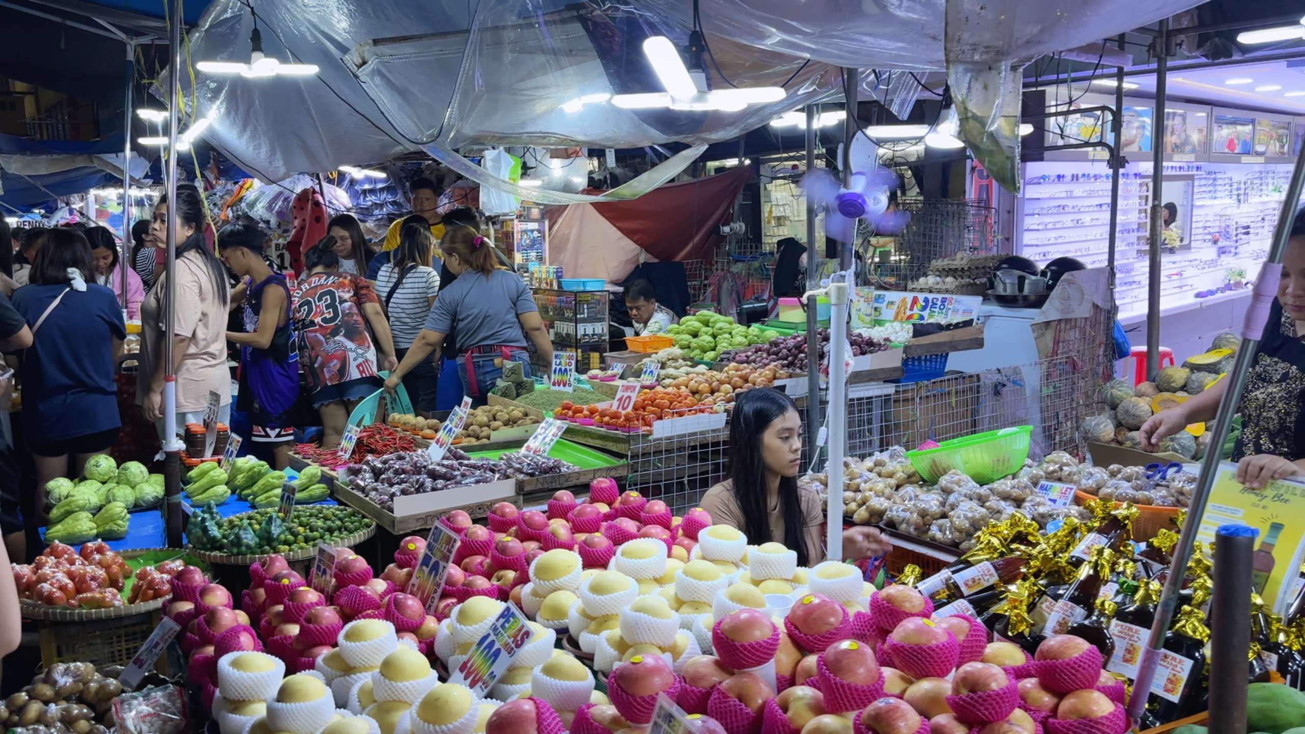 Abundant fruit stand displaying fresh produce under the glow of market lights.