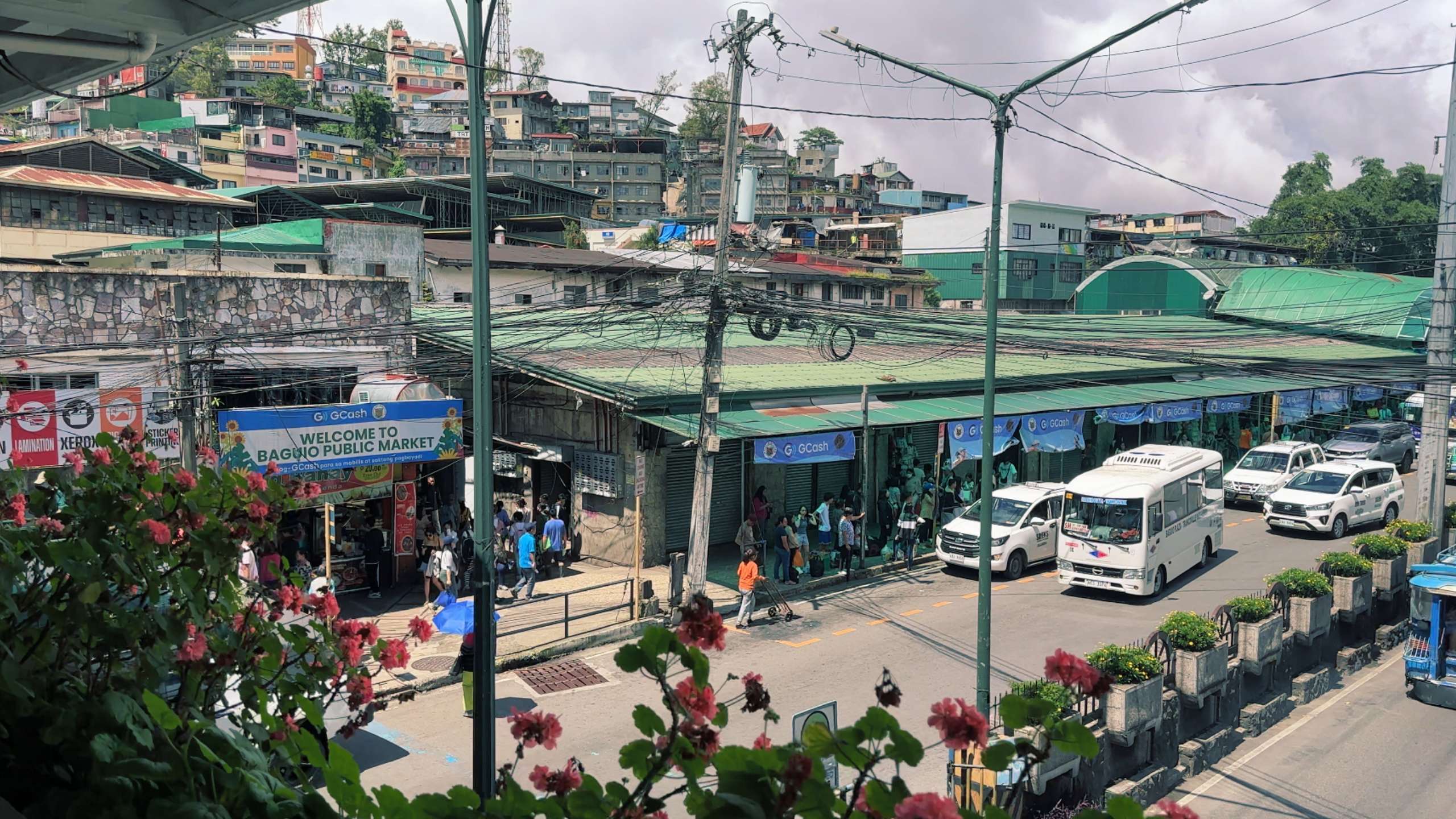 Overlooking a busy public market, a street filled with cars, buses, and greenery.