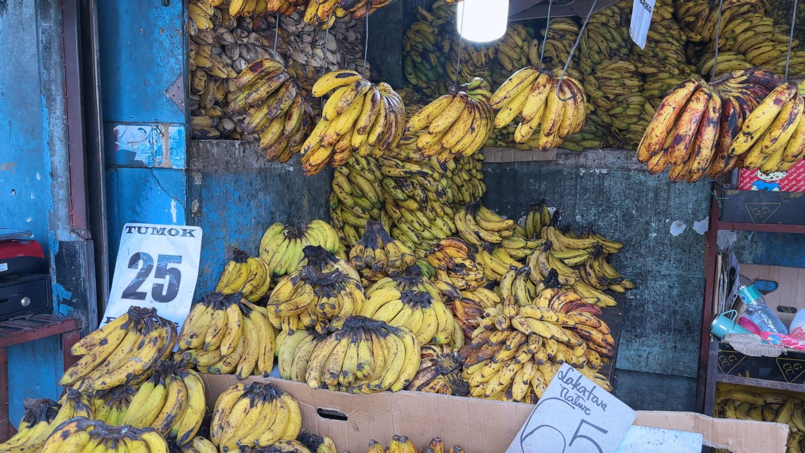 Bananas stacked and hanging in bunches at a vibrant fruit stall.