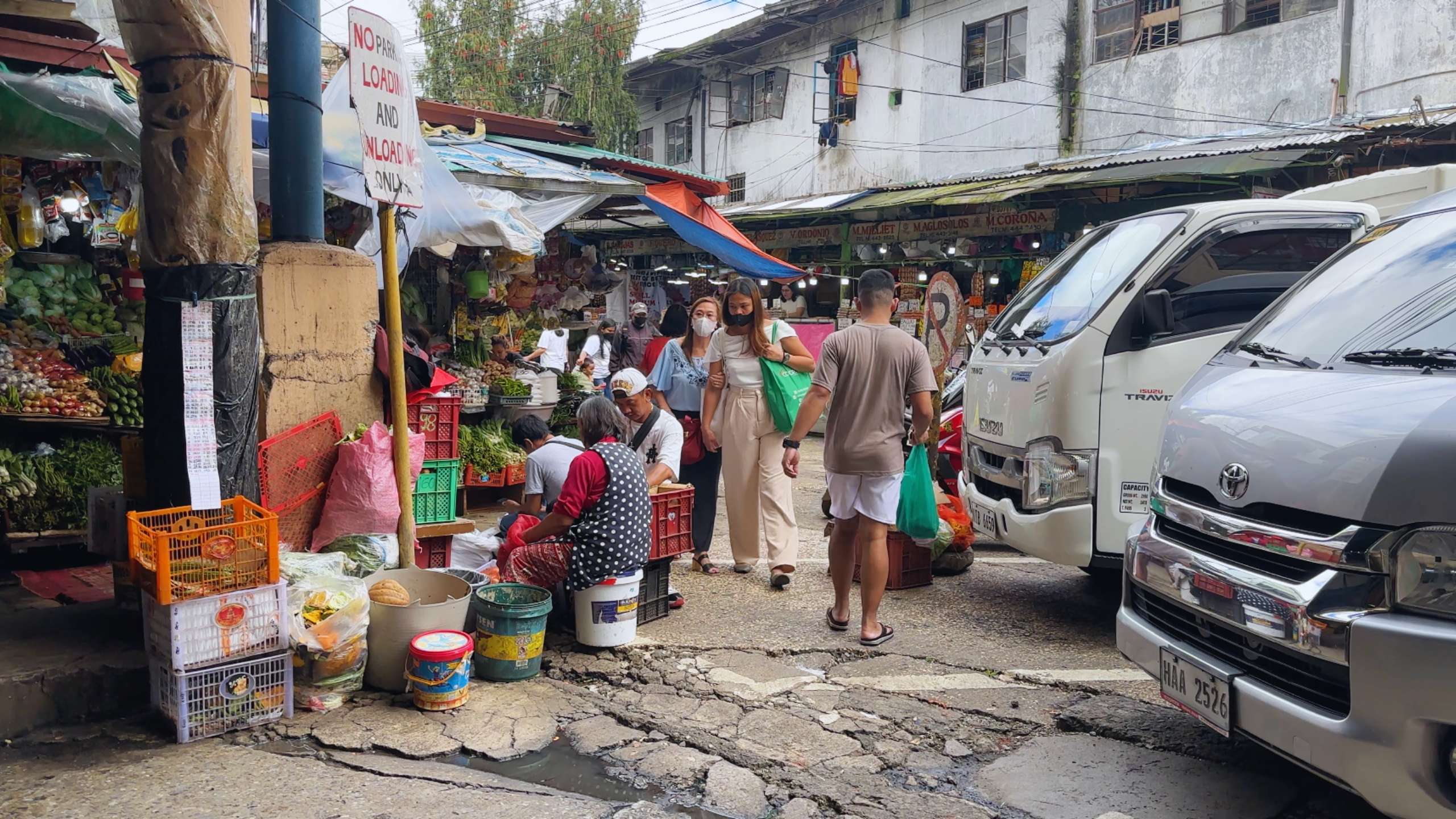 Outdoor market scene with vendors selling fresh produce and snacks.