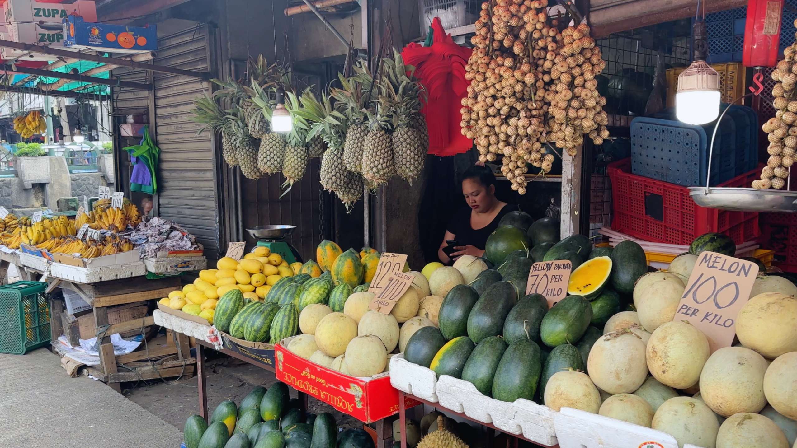 Fruit stand with pineapples, watermelons, and melons neatly arranged.