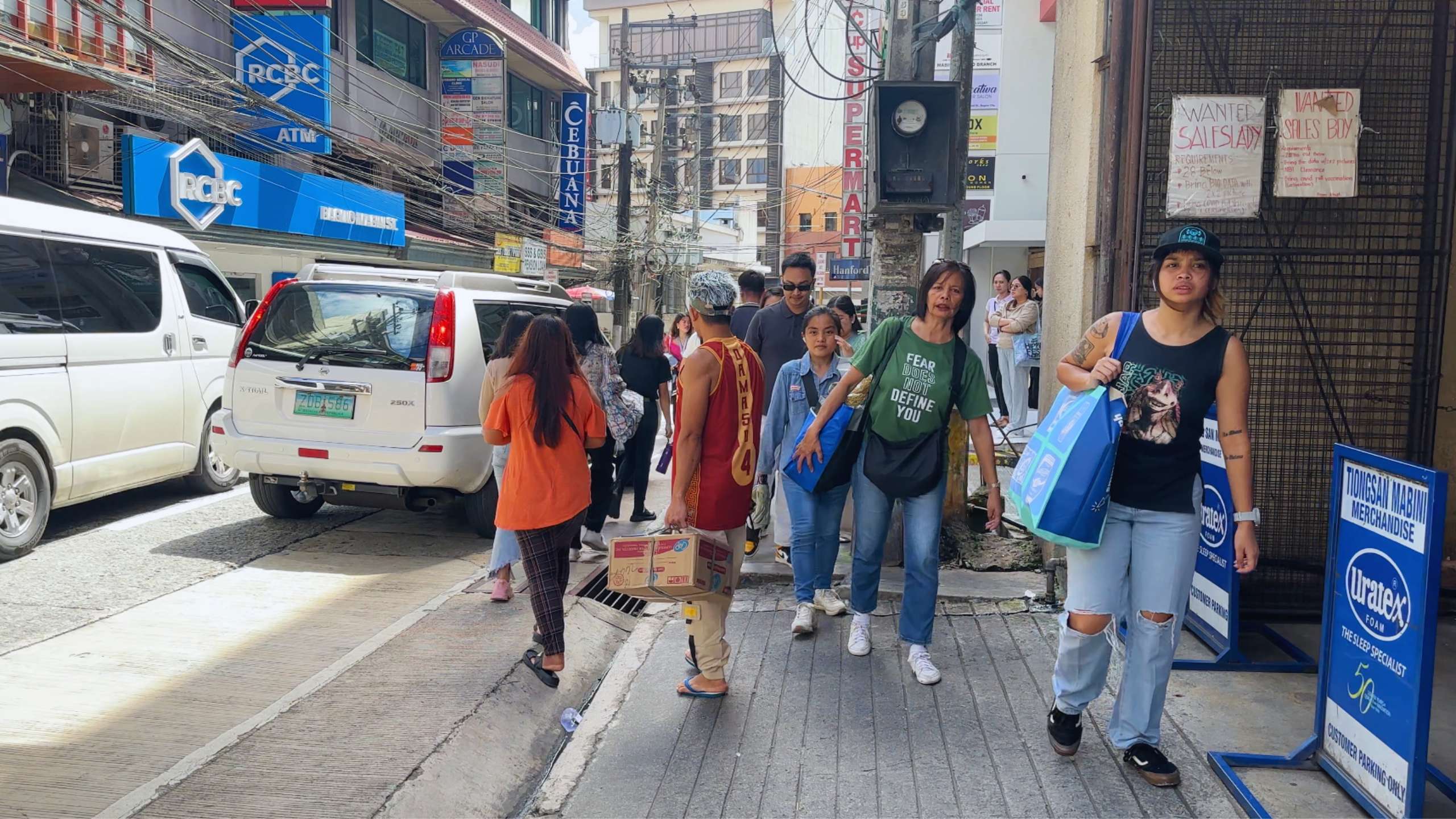 Pedestrians navigate a busy street filled with shops, vehicles, and activity.