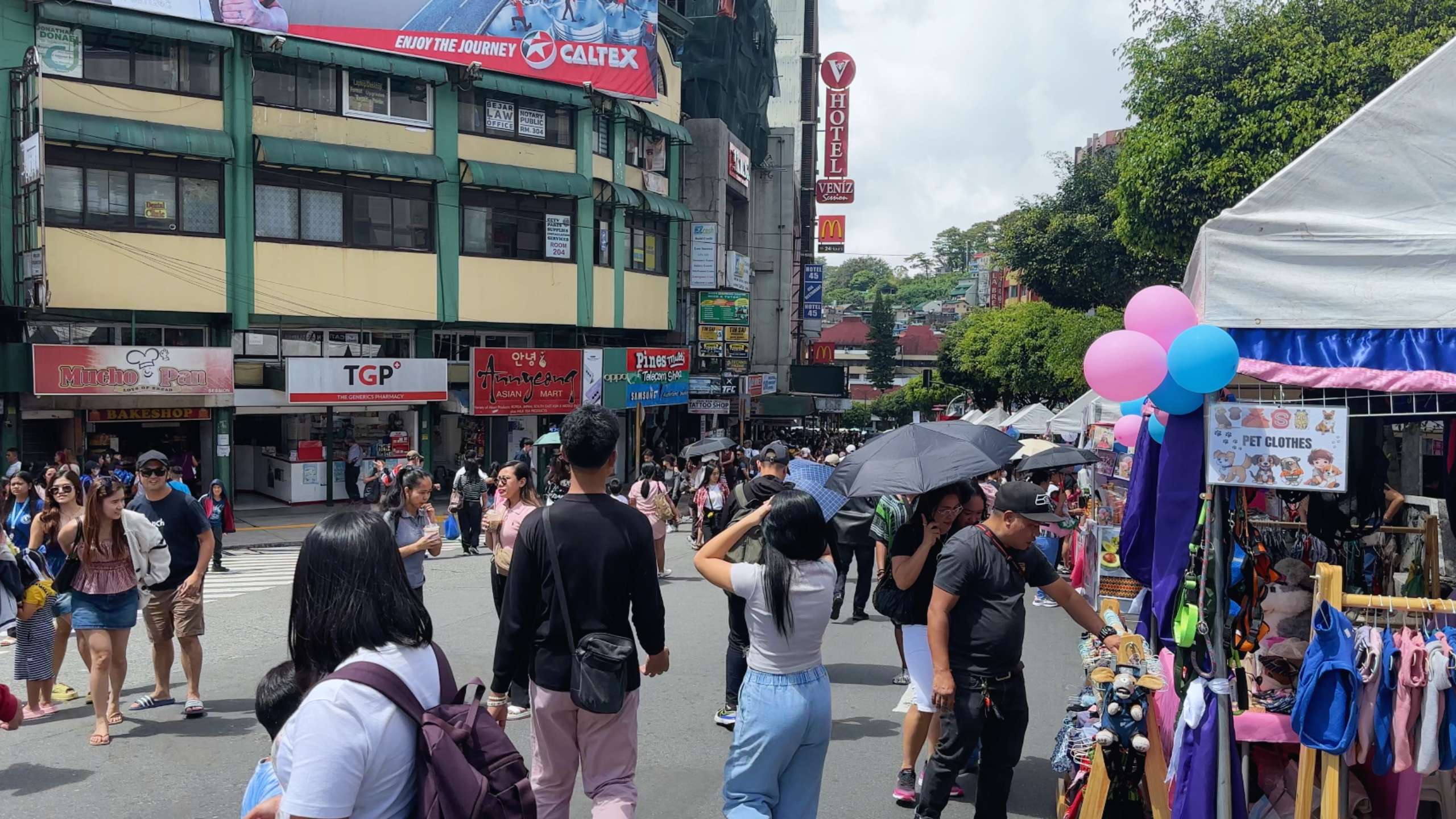 Shoppers and visitors browse a lively outdoor market filled with vibrant stalls.